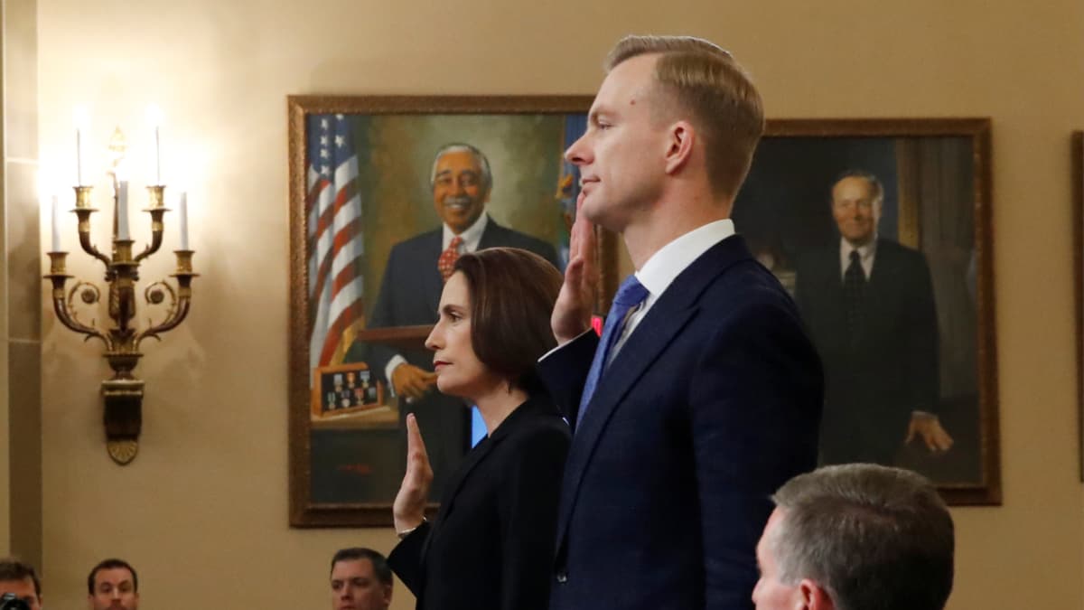 A man and a woman raise their right hands in front of an audience.