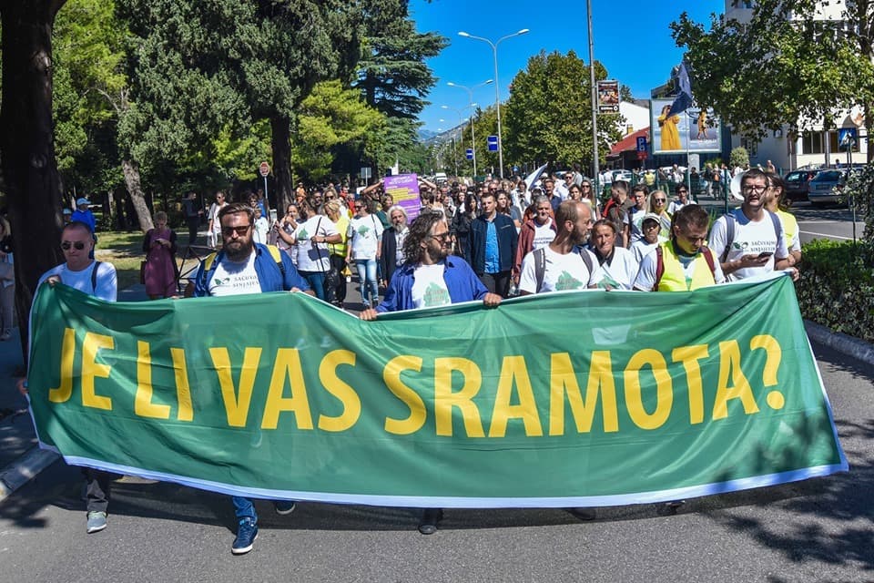 Protesters walk behind a large banner
