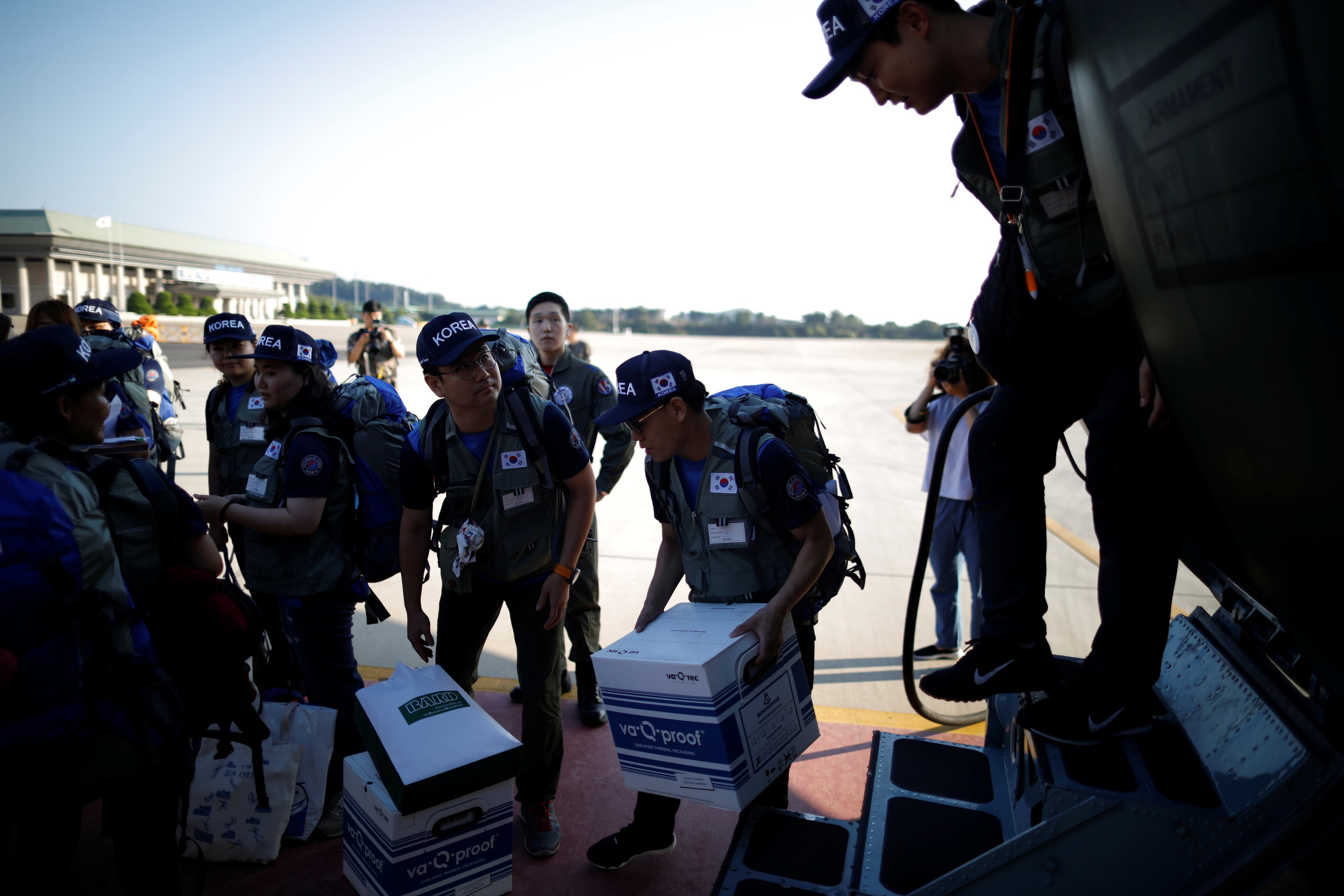 Military personnel carry disaster relief boxes.