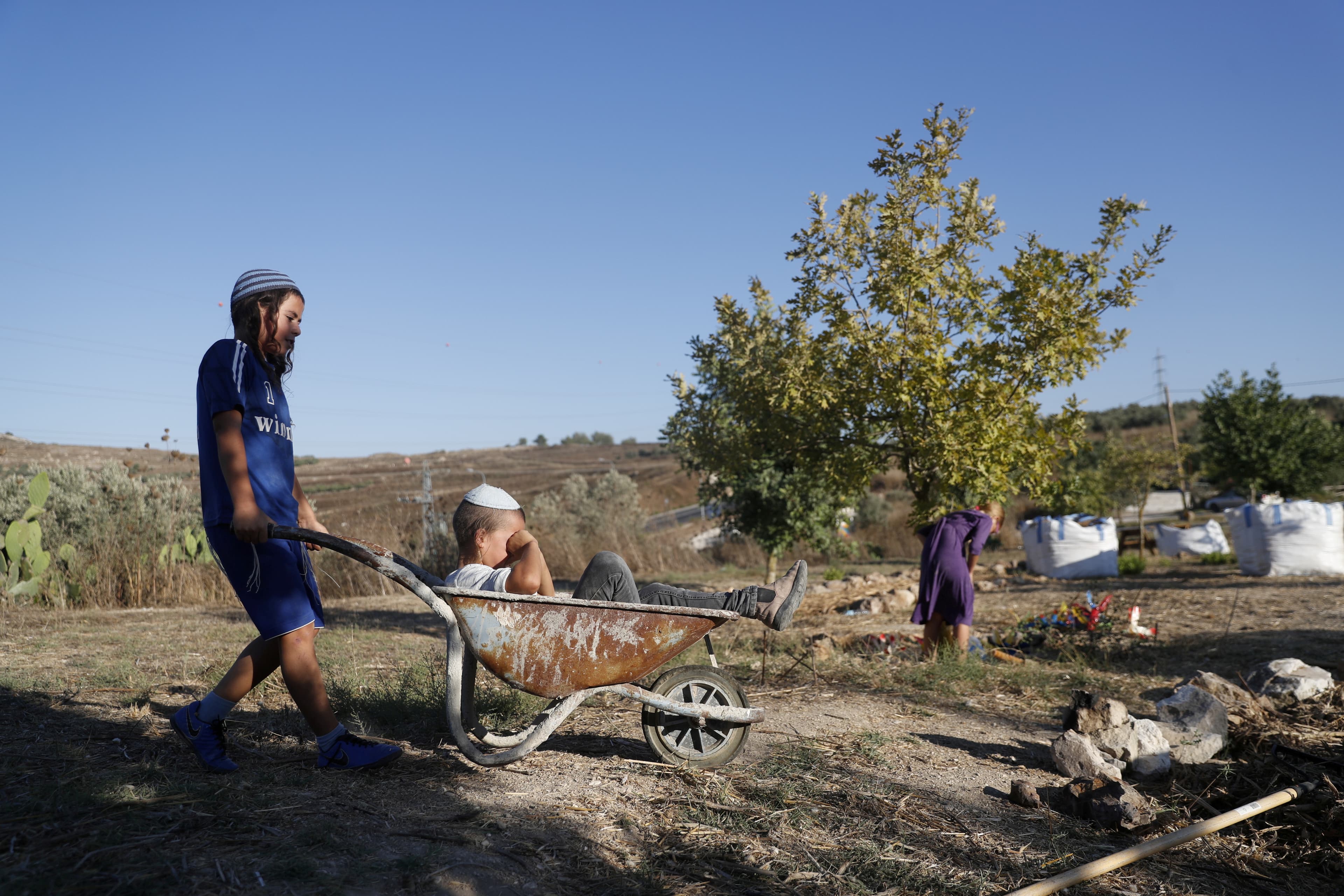Children play with a wheelbarrow.