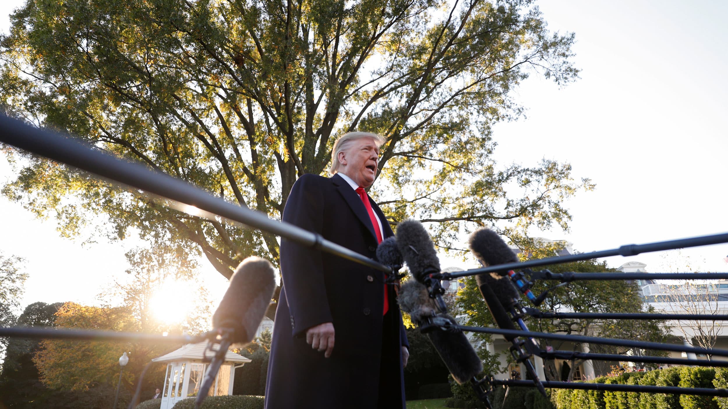 US President Donald Trump stands amid microphones outside