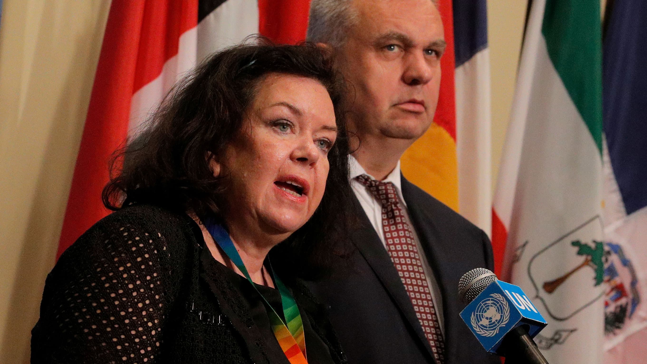 A woman speaks at a podium with a man behind her