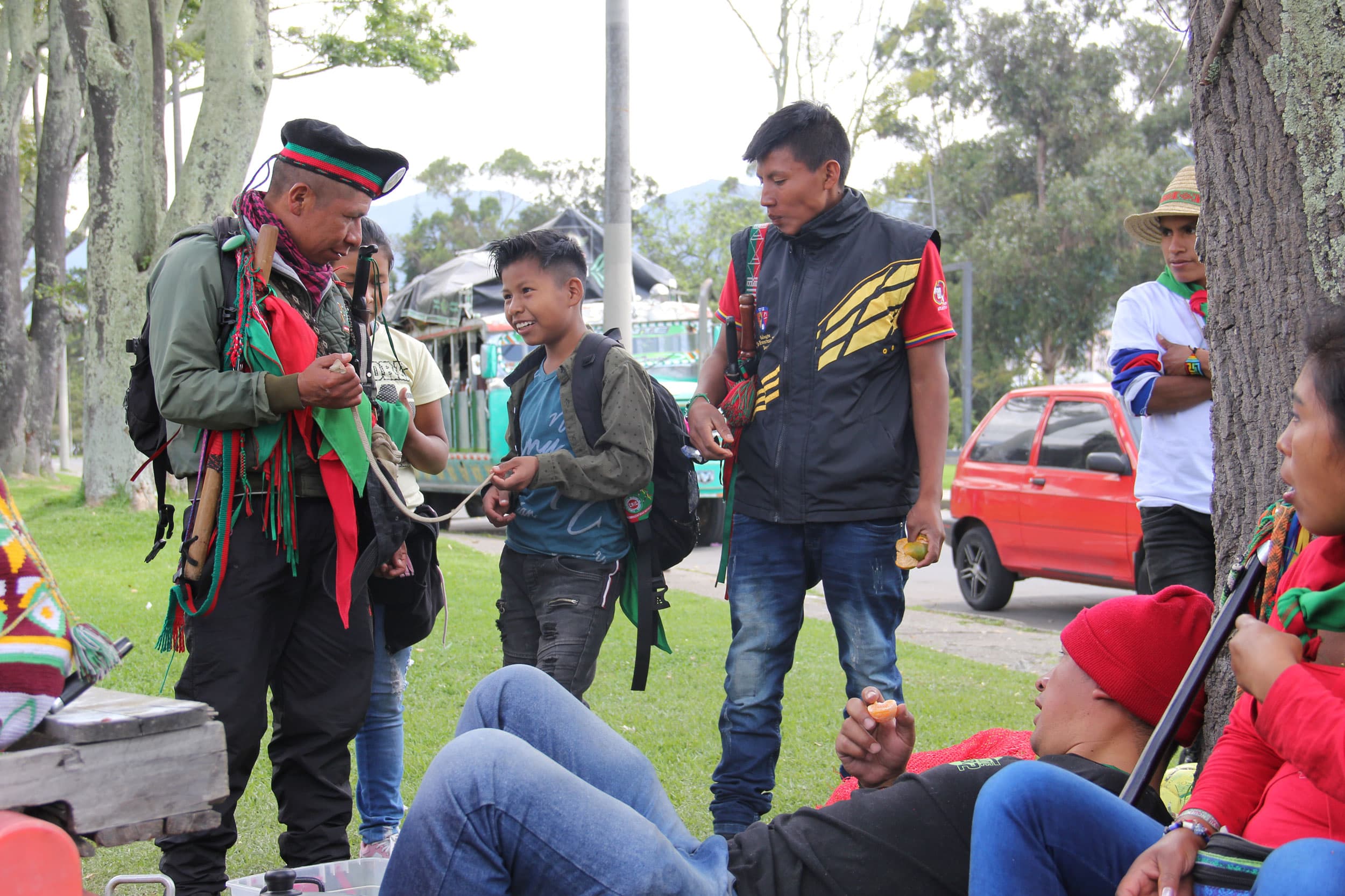 Jose Albeiro Camayo is shown speaks to two younger men outside on a tree-lined street.