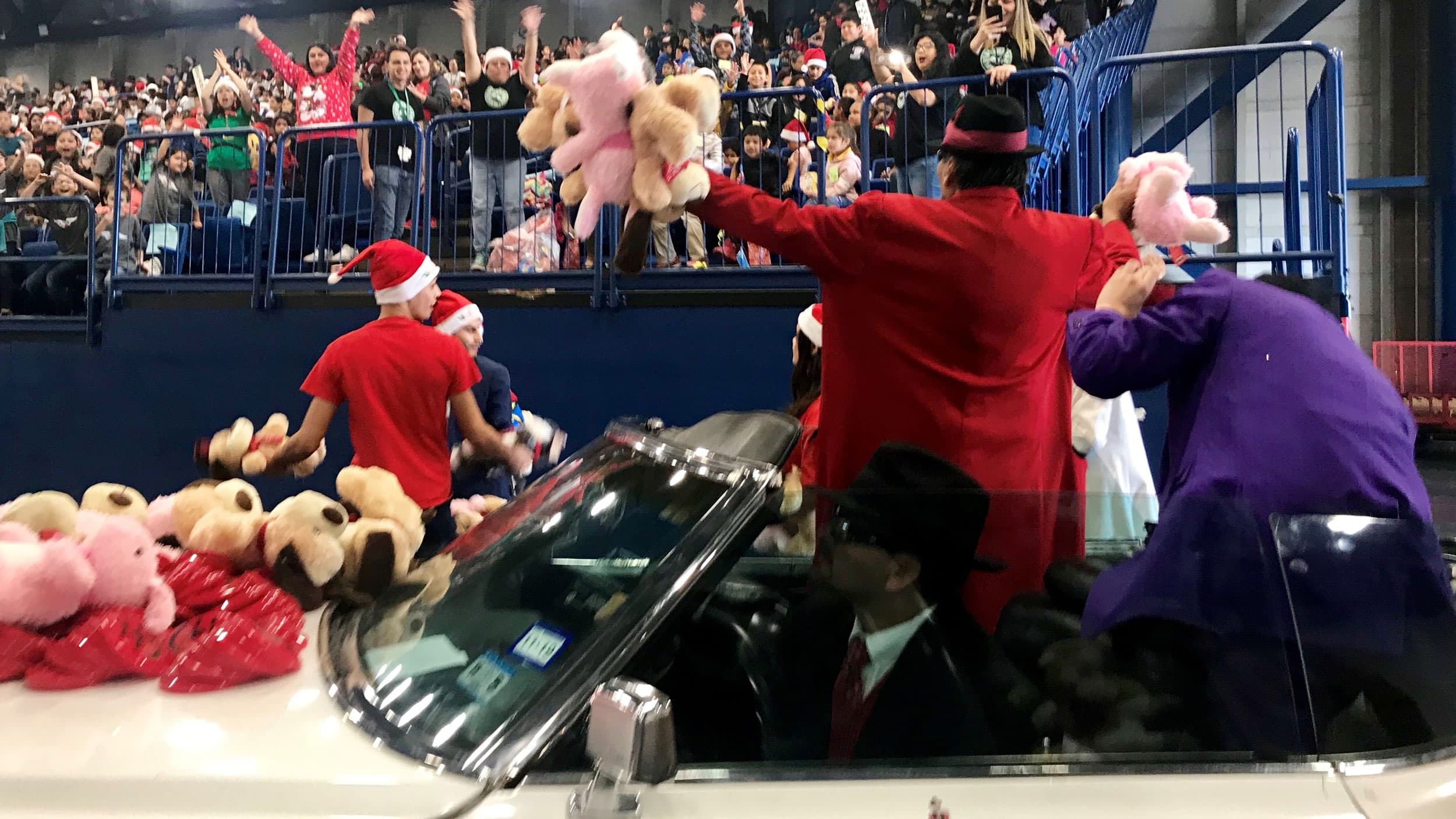Pancho Claus is shown in a red jacket and black hat with his hands out stretch and holding stuffed animals.