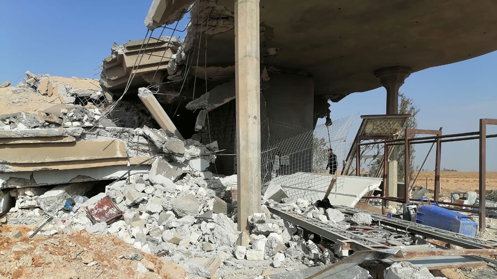 A destroyed cement building is shown with rubble all over.