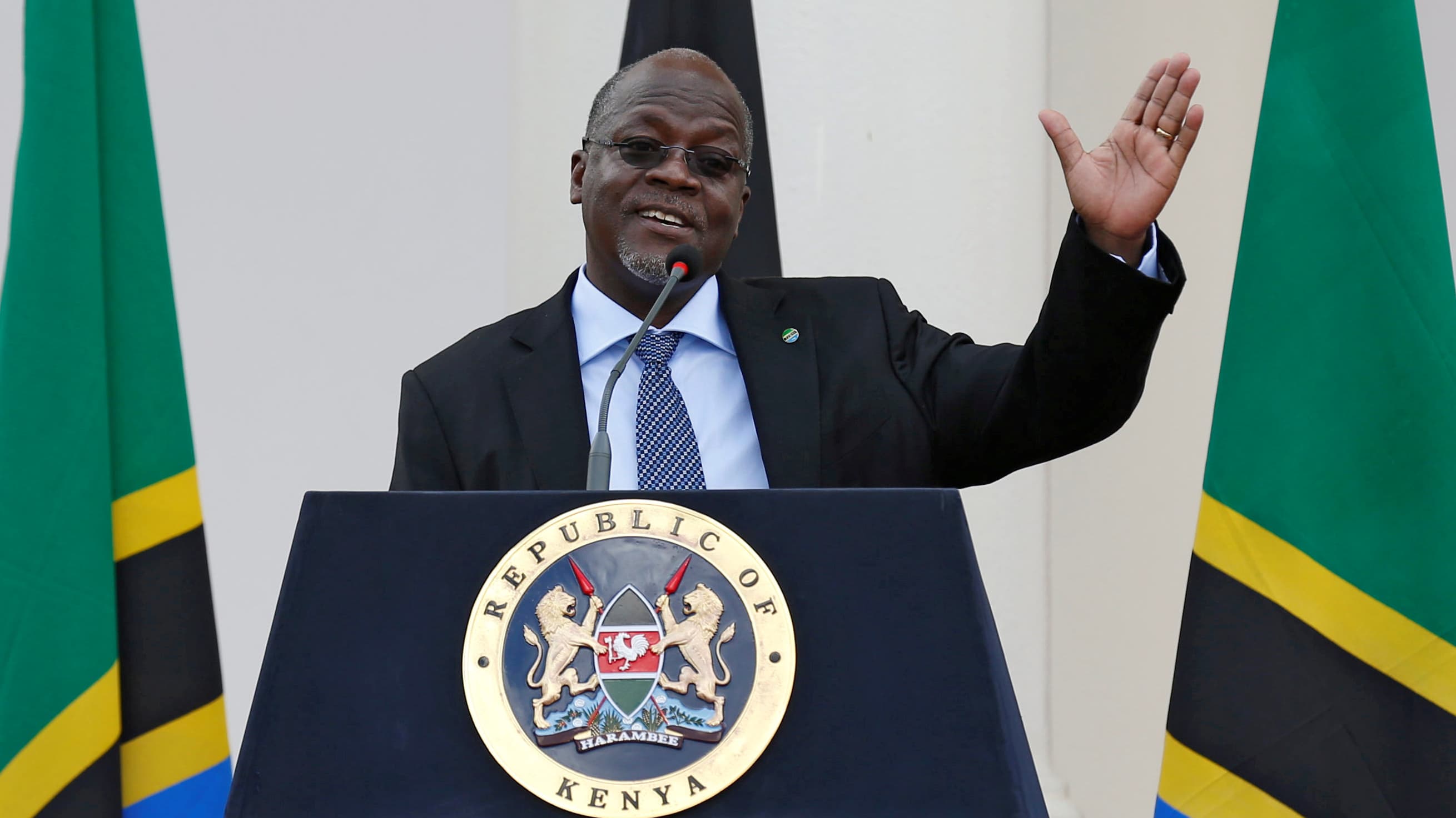 President Magufuli stands in front of a podium.