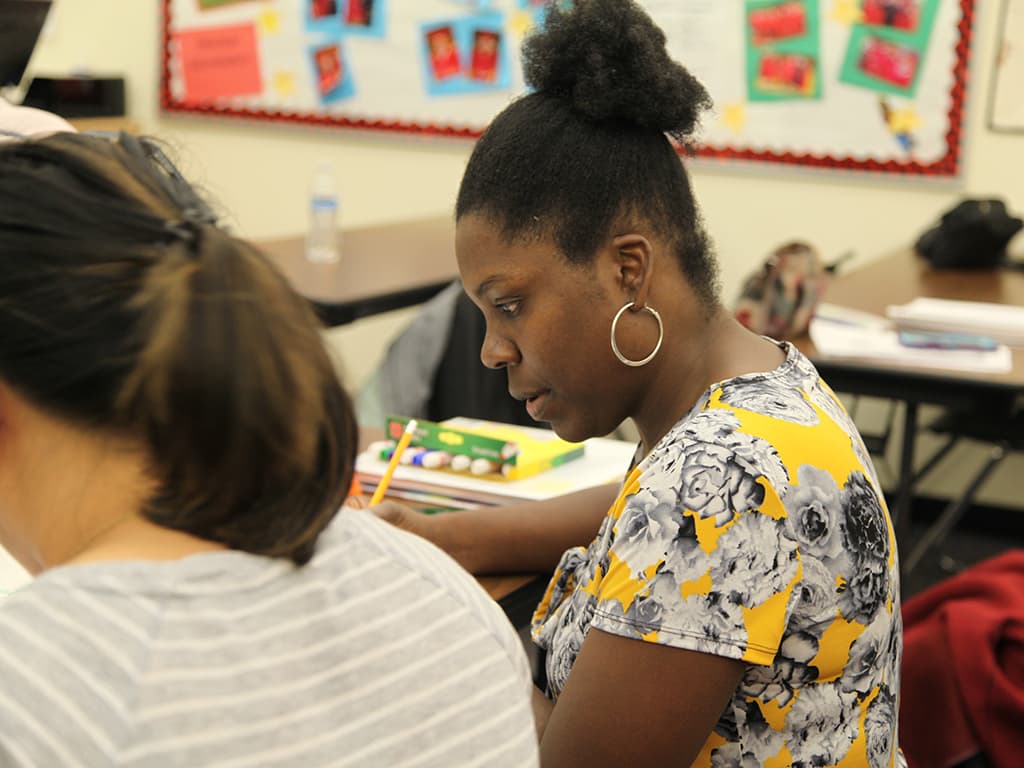 A woman talks in front of a class.