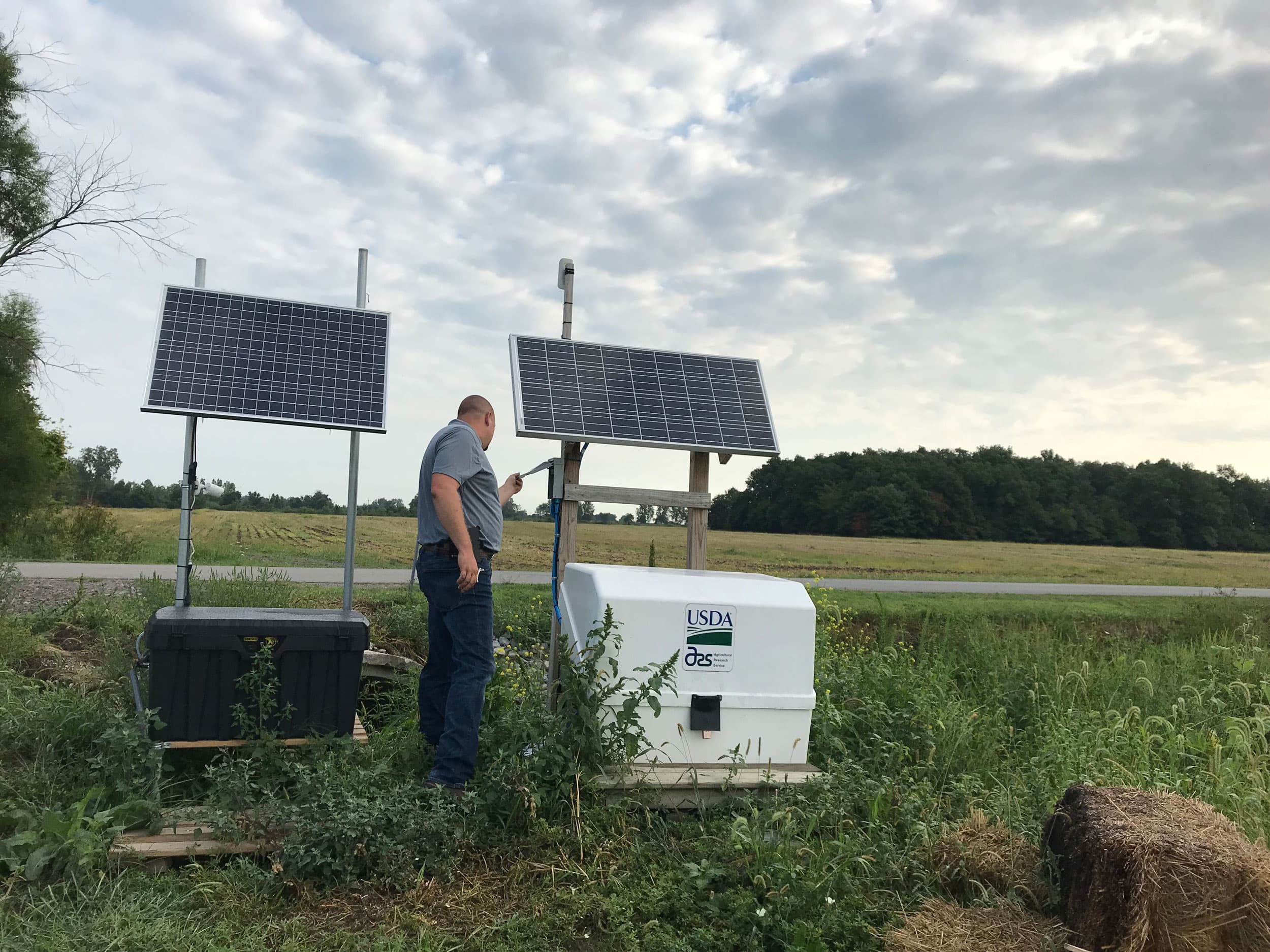 A man is shown standing between two machines with solar panels on top.