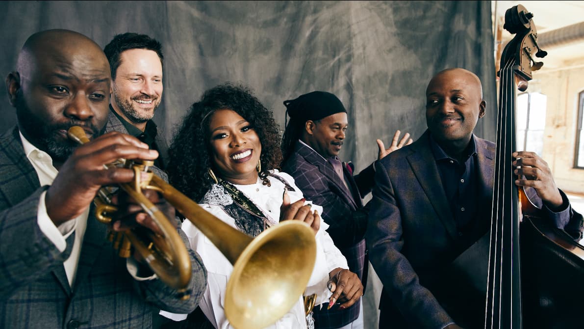 Five people pose for a photo with music instruments.