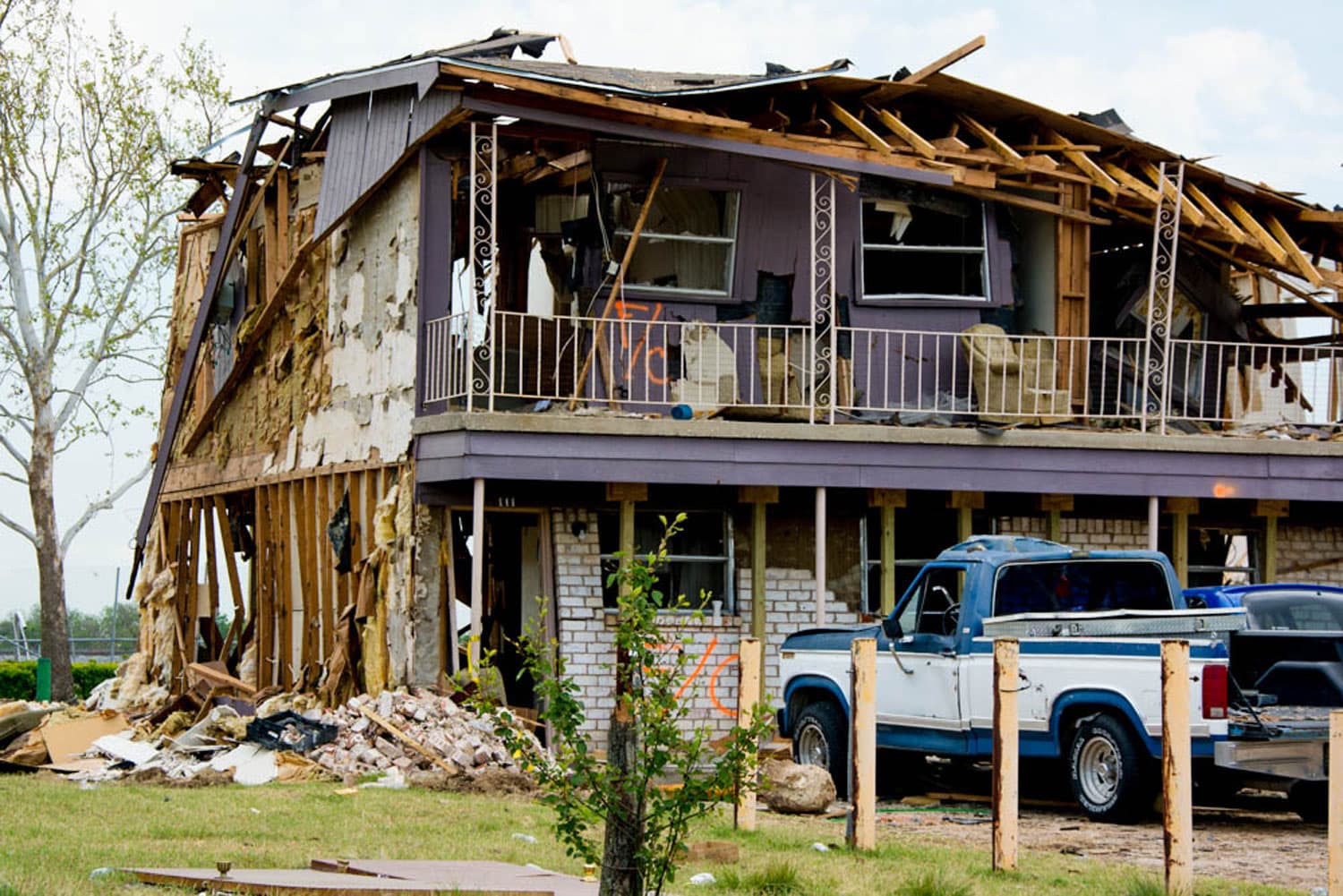 A home is shown with the roof falling in and a wall heavily damaged.
