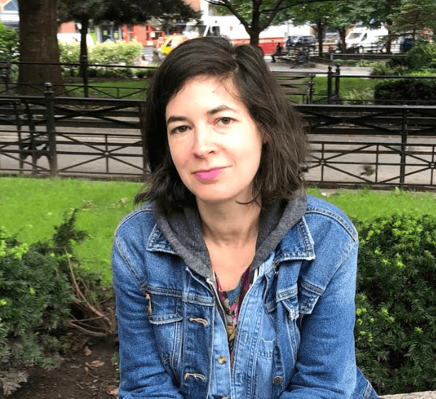 A woman with a jean jacket posses for a photo.
