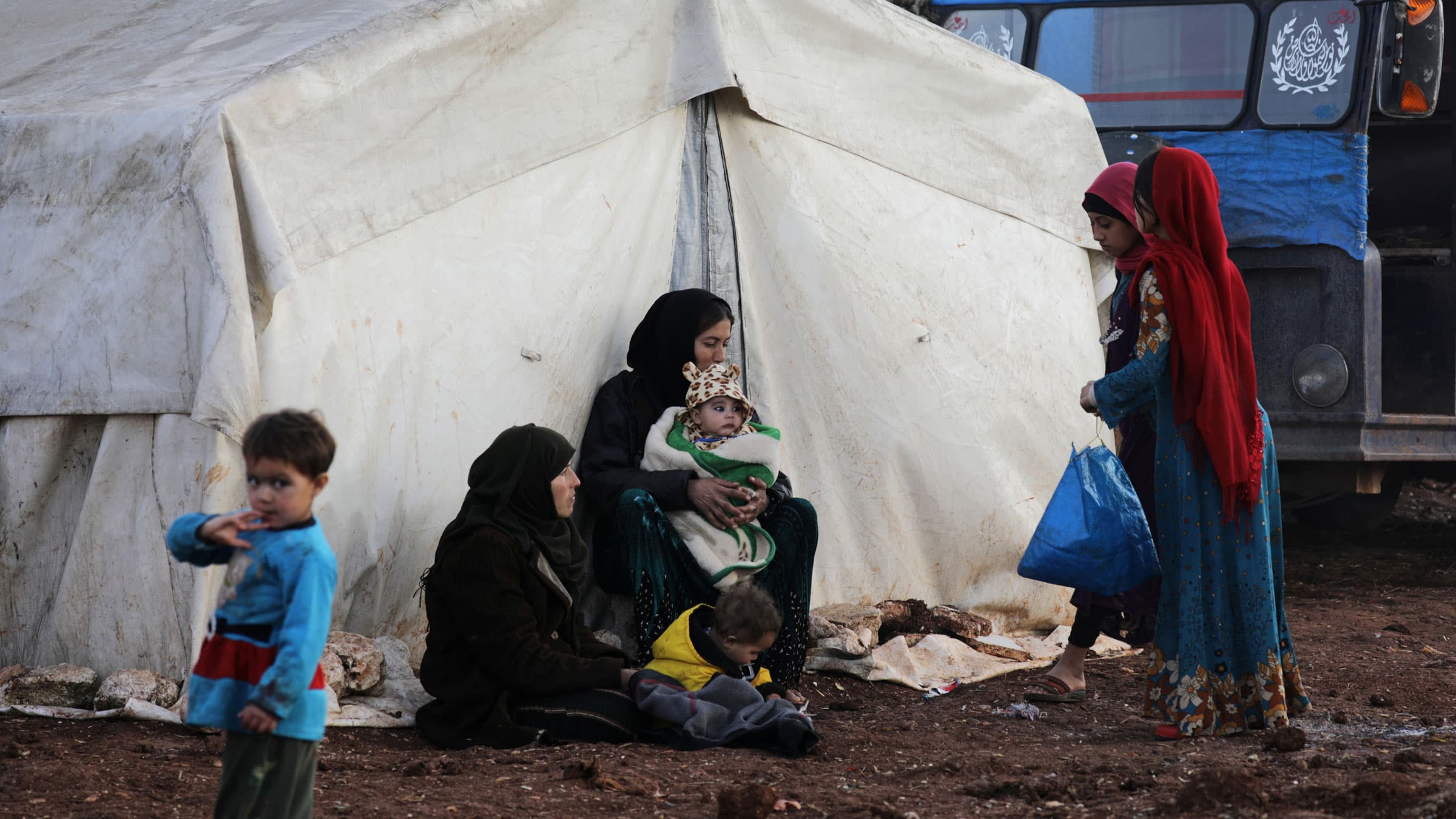 Internally displaced people stand outside tents at a makeshift camp in Azaz, Syria, Feb. 19, 2020.