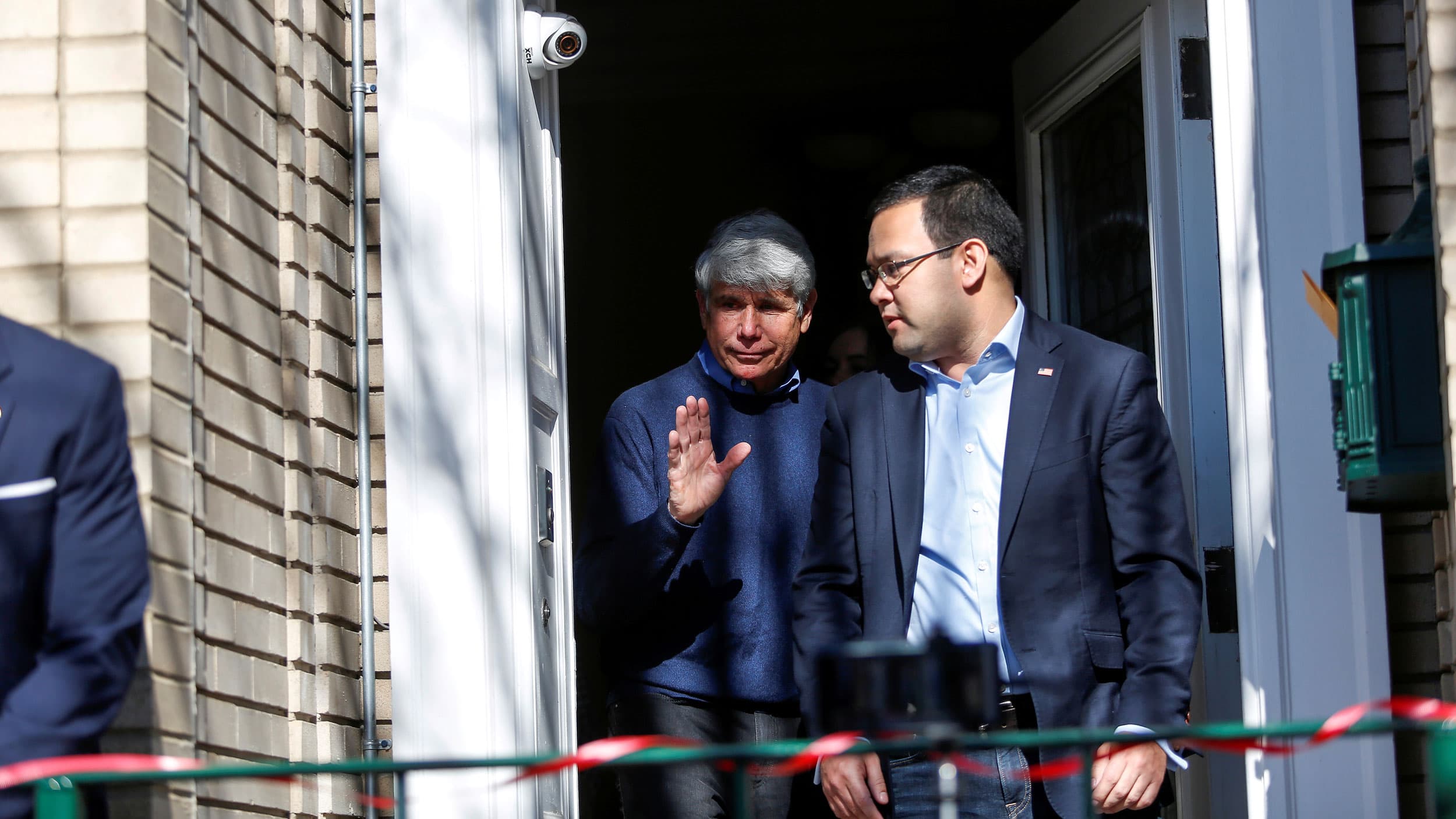 A man exits a door with another man around him.