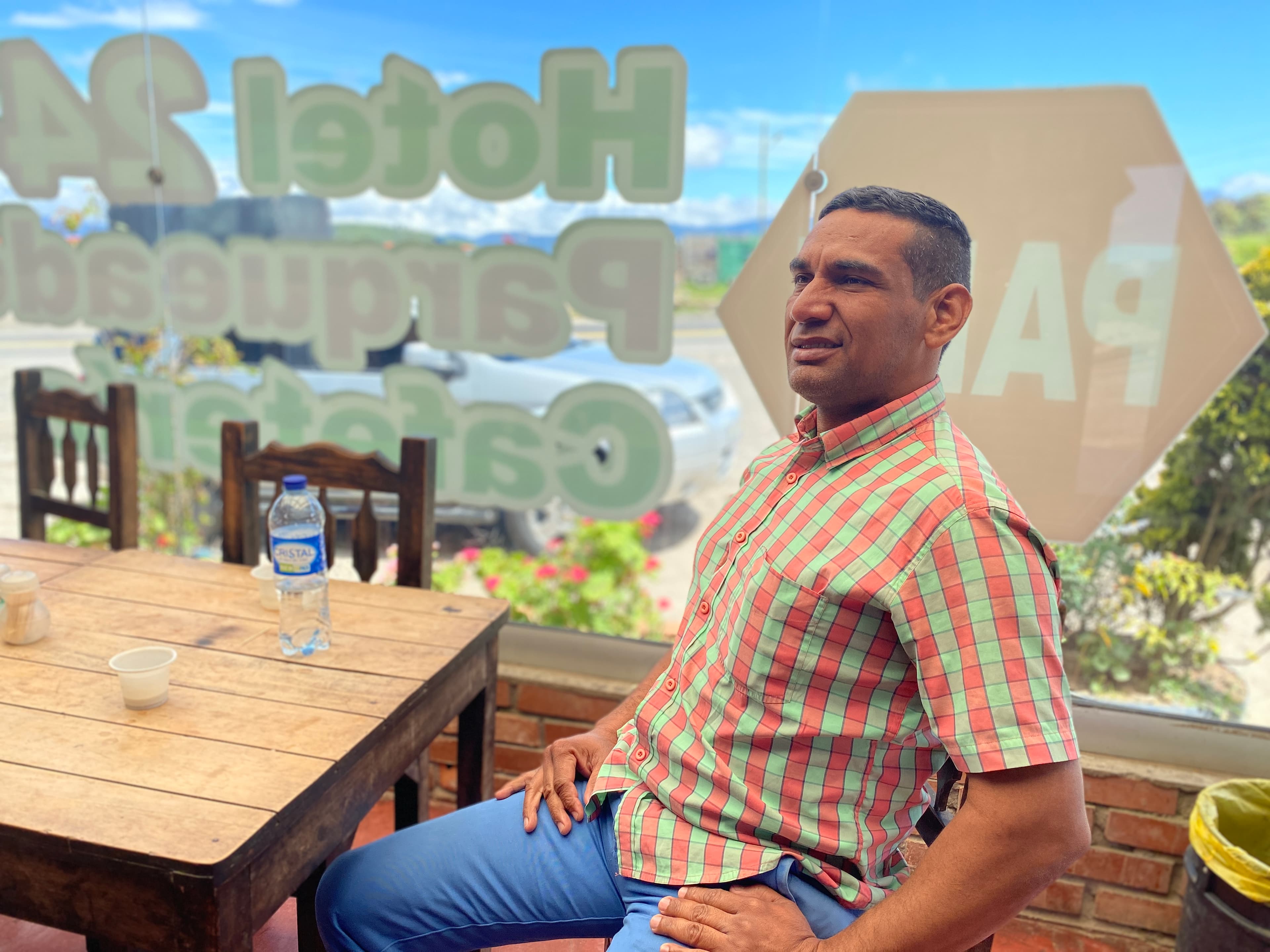 A man sits at a table at a restaurant with a plastic bottle of water.