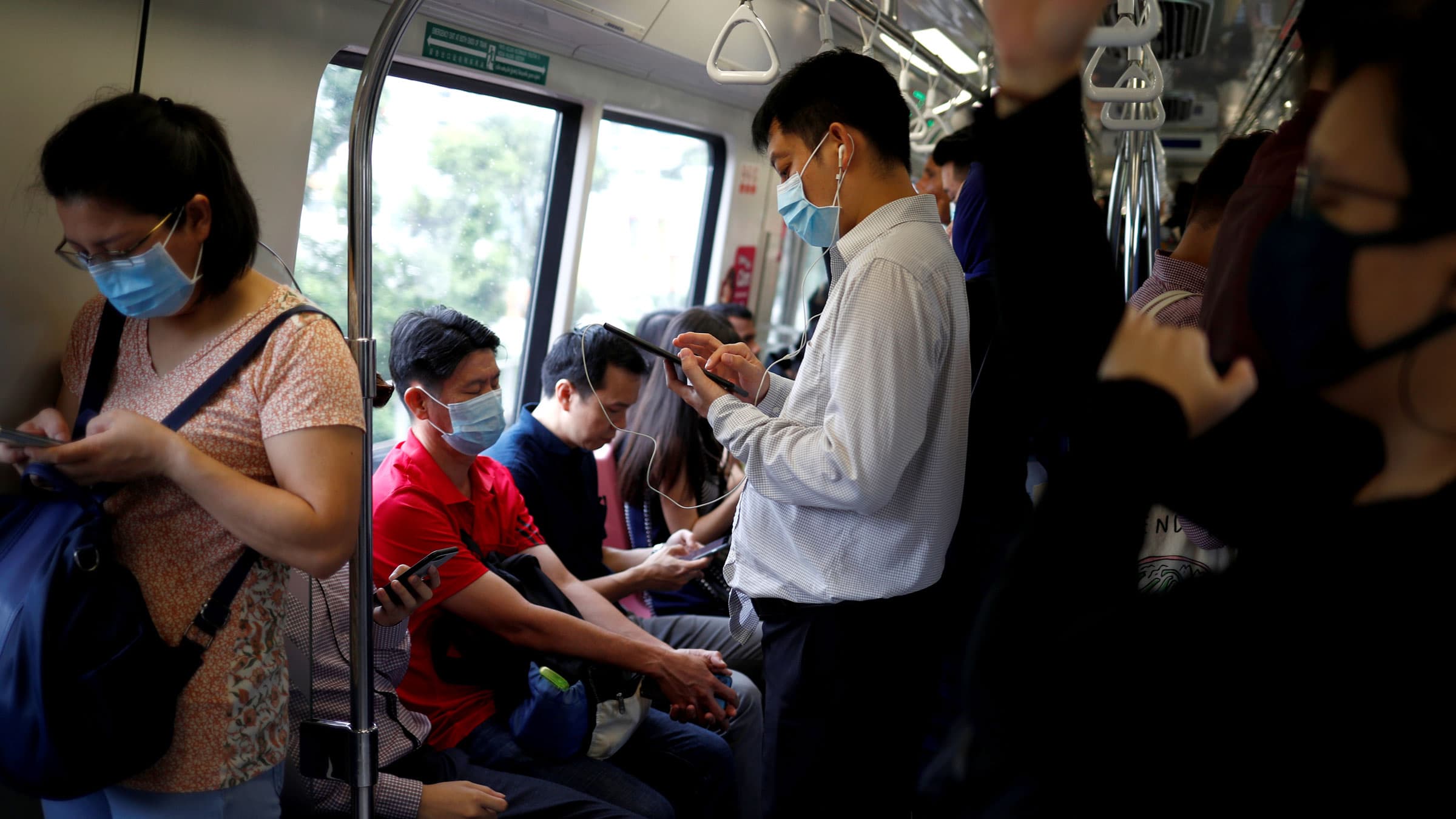 Commuters wearing masks in precaution of the coronavirus outbreak are pictured in a train during their morning commute in Singapore, Feb. 18, 2020.