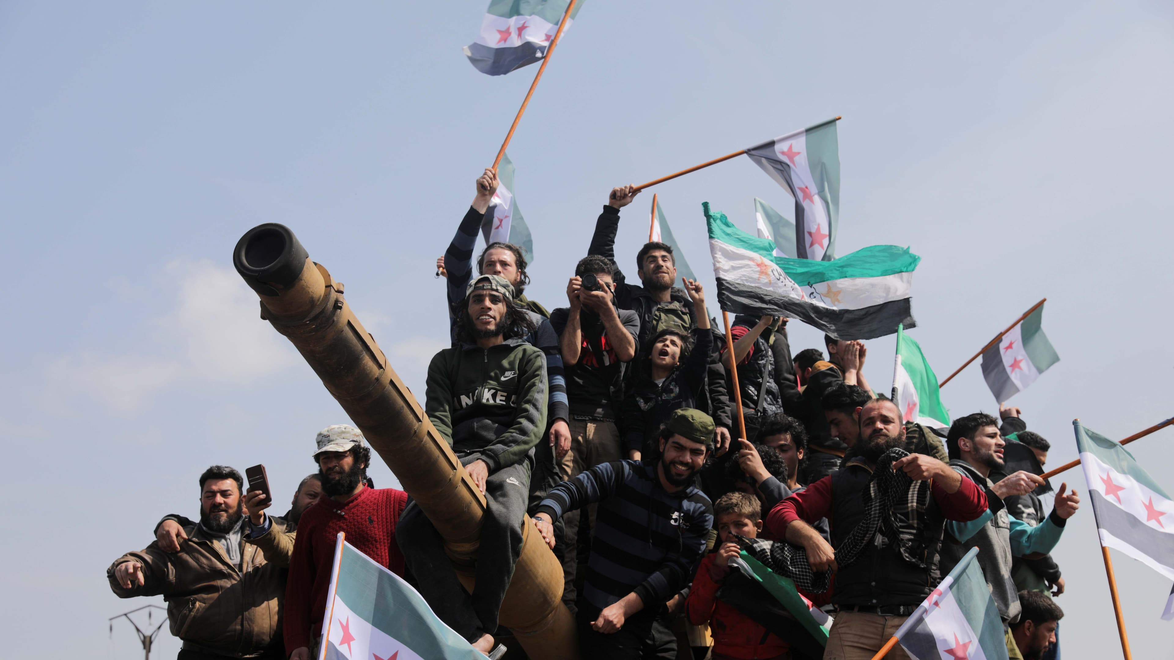 People stand on a Turkish military vehicle during a protest against an agreement on joint Russian and Turkish patrols, at M4 highway in Idlib province, Syria, March 15, 2020.