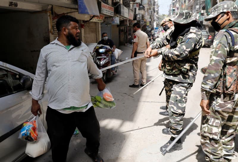 Police officers wield their batons against a man as a punishment for breaking the lockdown rules