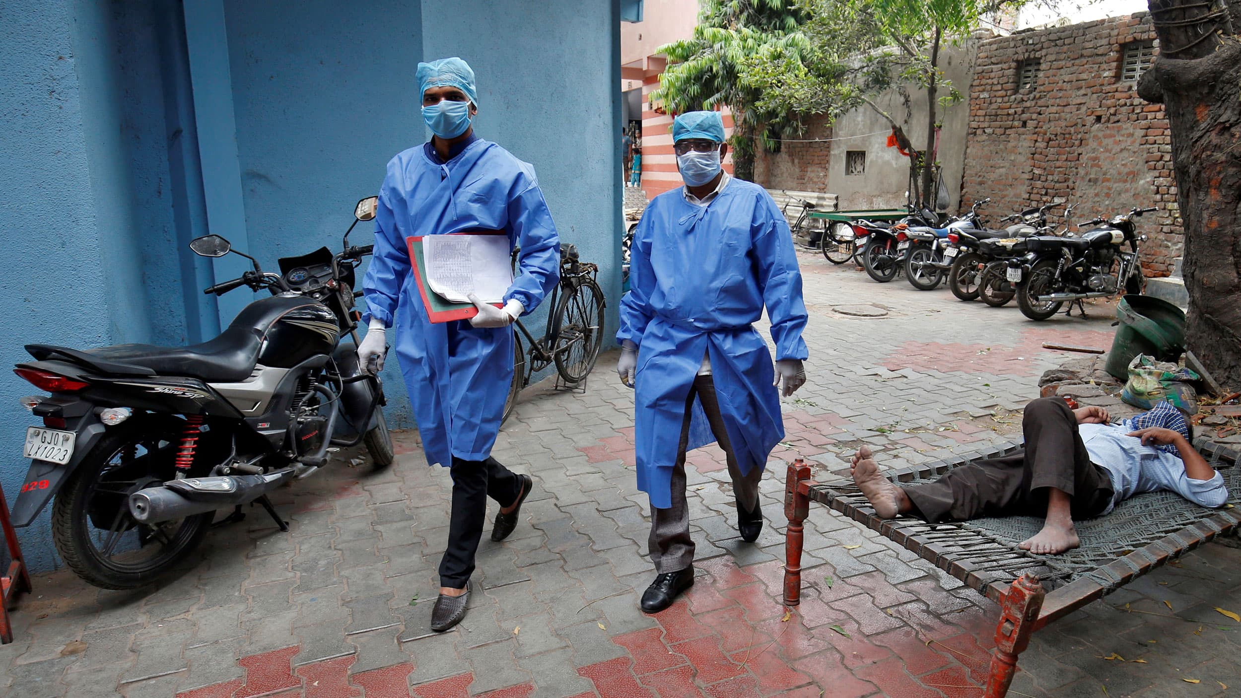 Police officers in protective suits arrive in a residential area to check on people