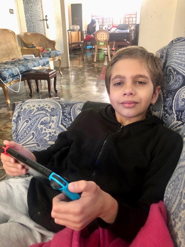 Mark Anton of Lebanon shows off his Switch gaming console where he’s playing a lot of video games these days. In the background, his older sister takes an online class.