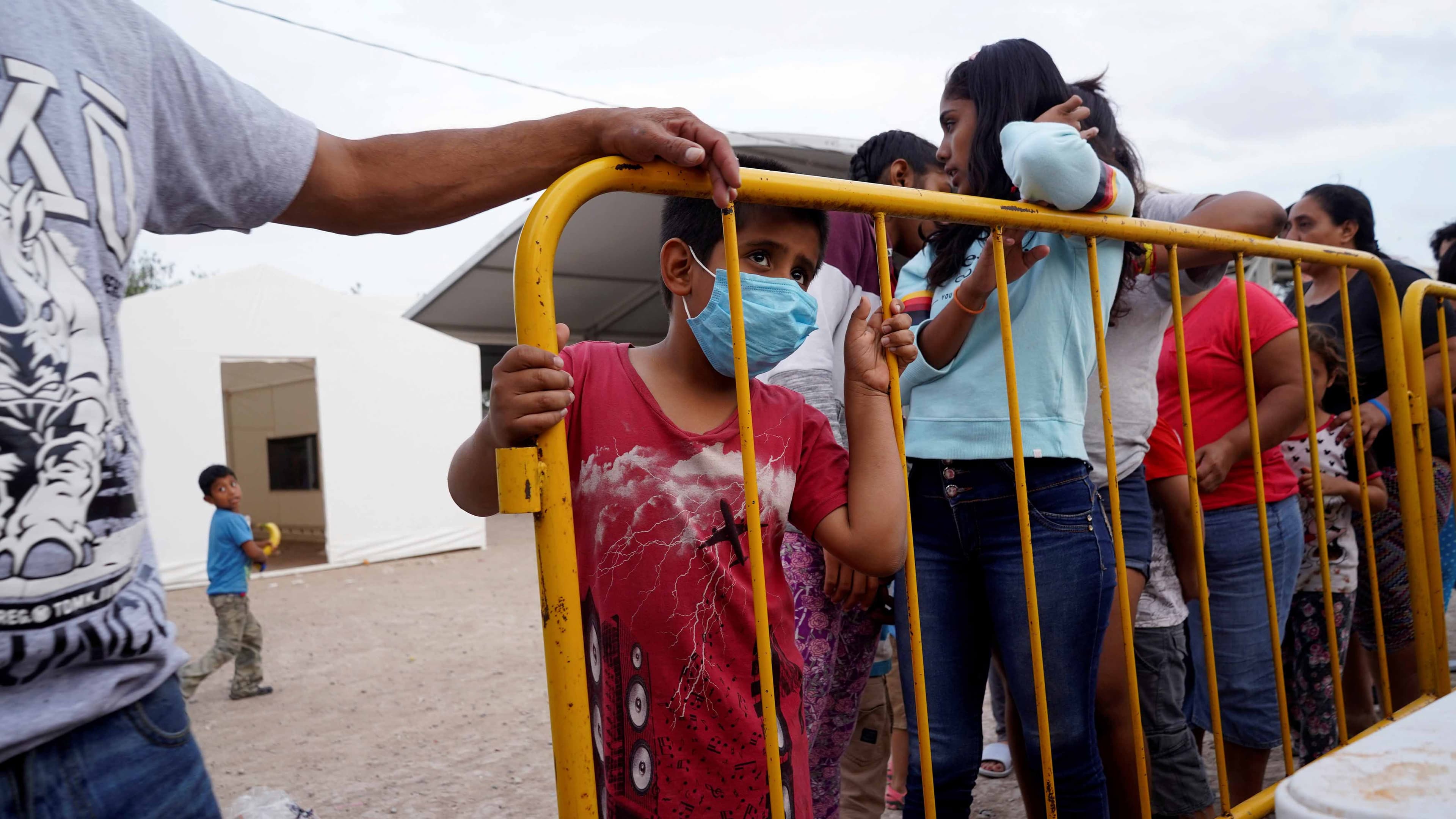 A migrant child, who is seeking asylum in the US, wears a protective mask as he stands in line for food, amid an outbreak of the coronavirus disease (COVID-19), in the migrant camp of Matamoros, Mexico, April 1, 2020.
