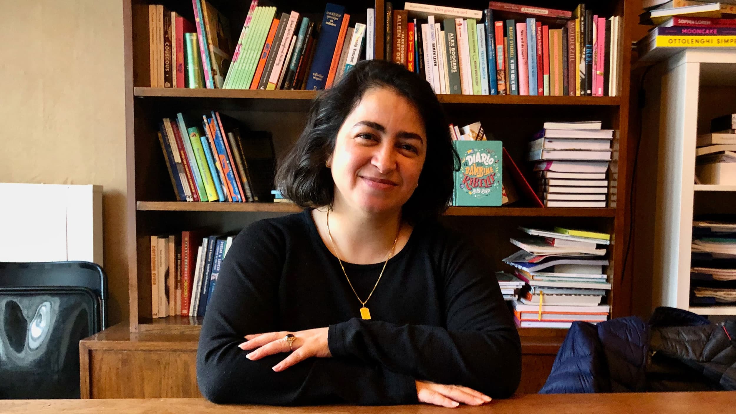 A midshot of a woman in front of a bookshelf