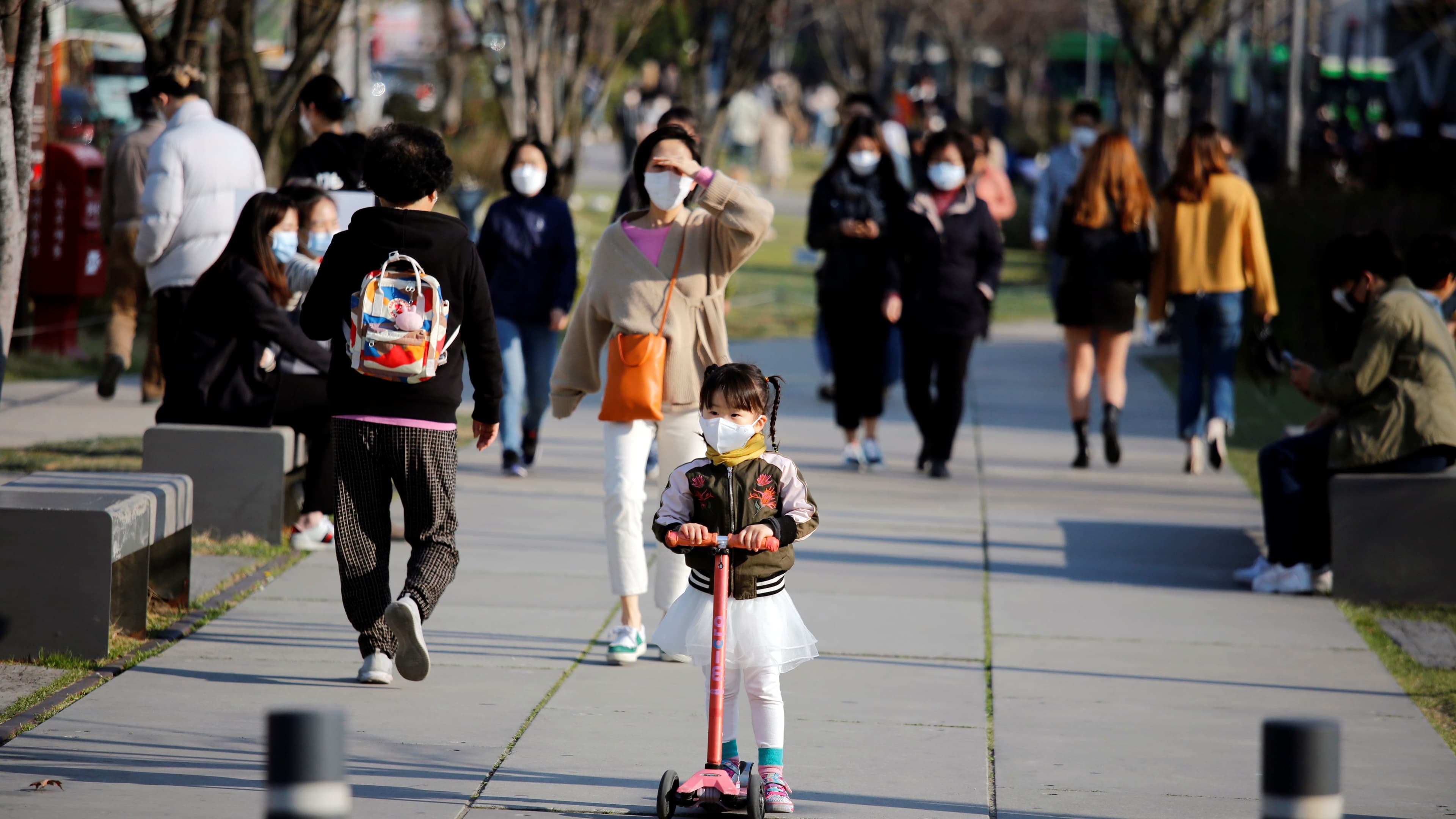 A girl wearing a protective face mask to prevent contracting the coronavirus disease (COVID-19) rides a toy kick scooter at a park in Seoul, South Korea, April 3, 2020.