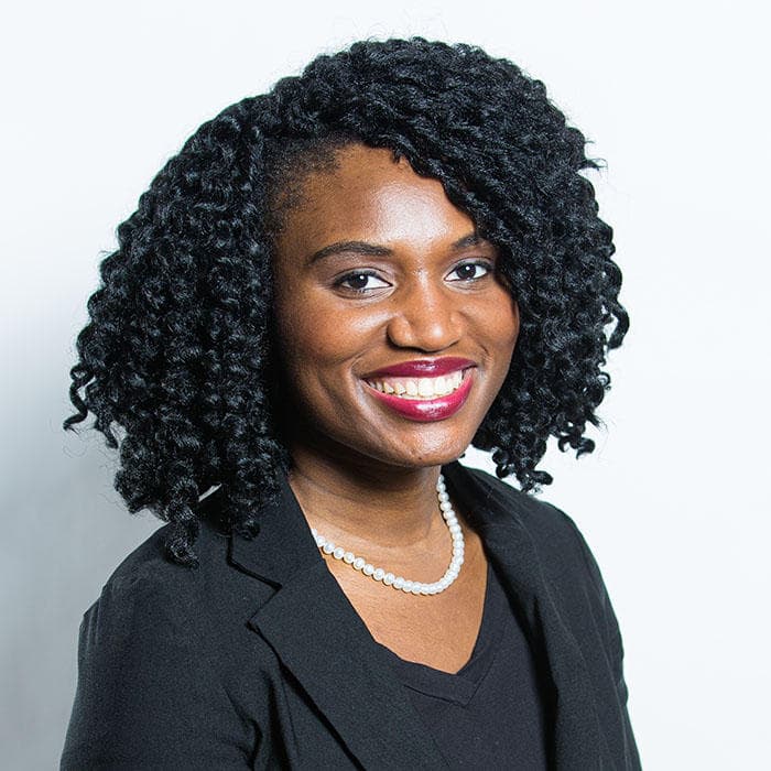 A woman with curly hair posses for a photo.