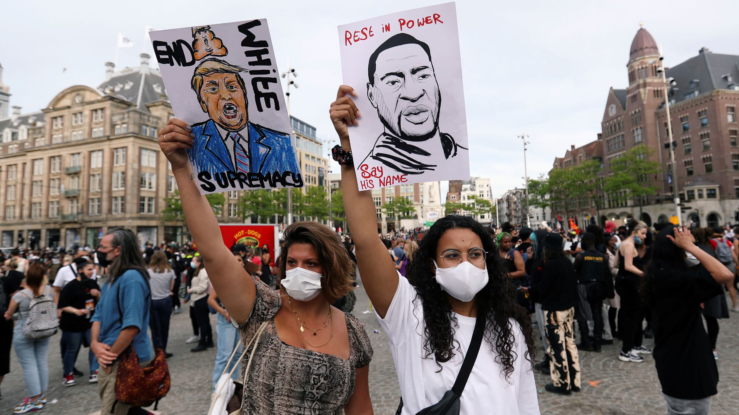 Women hold up a poster of US President Donald Trump reading "End white supremacy" and George Floyd reading "Rest in power. Say his name"