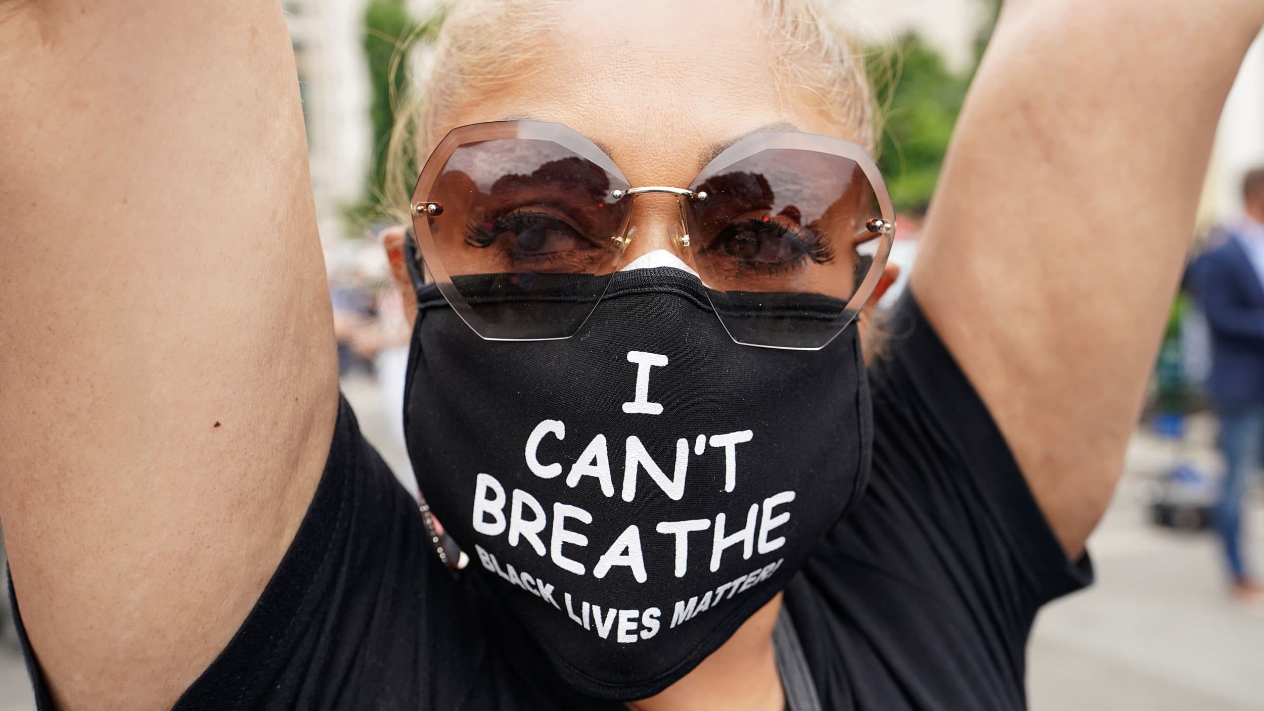 A close of a woman with a face mask reading "I can't breathe Black Lives Matter"