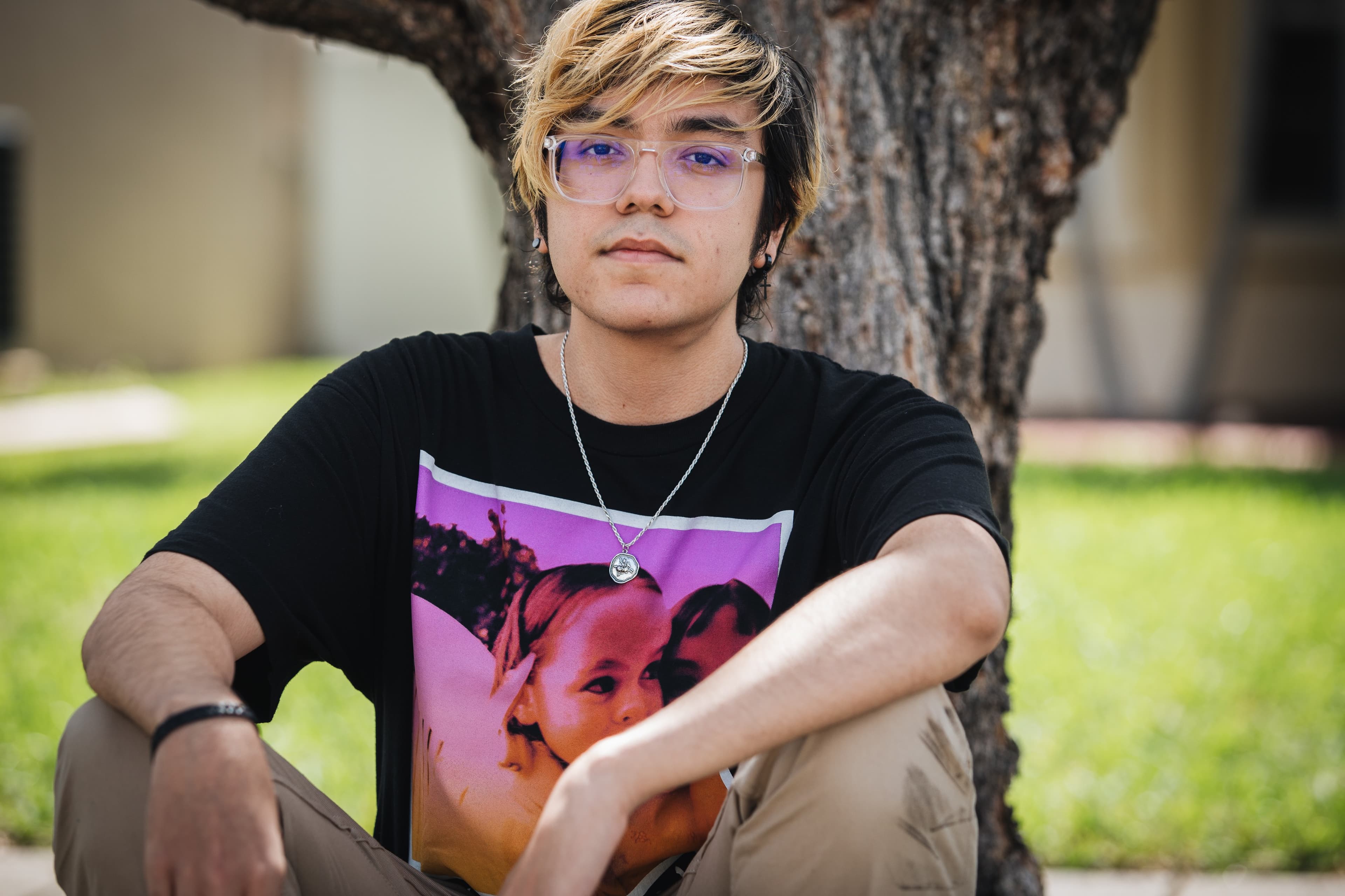 A young man in a black shirt and glasses posses for a photo.