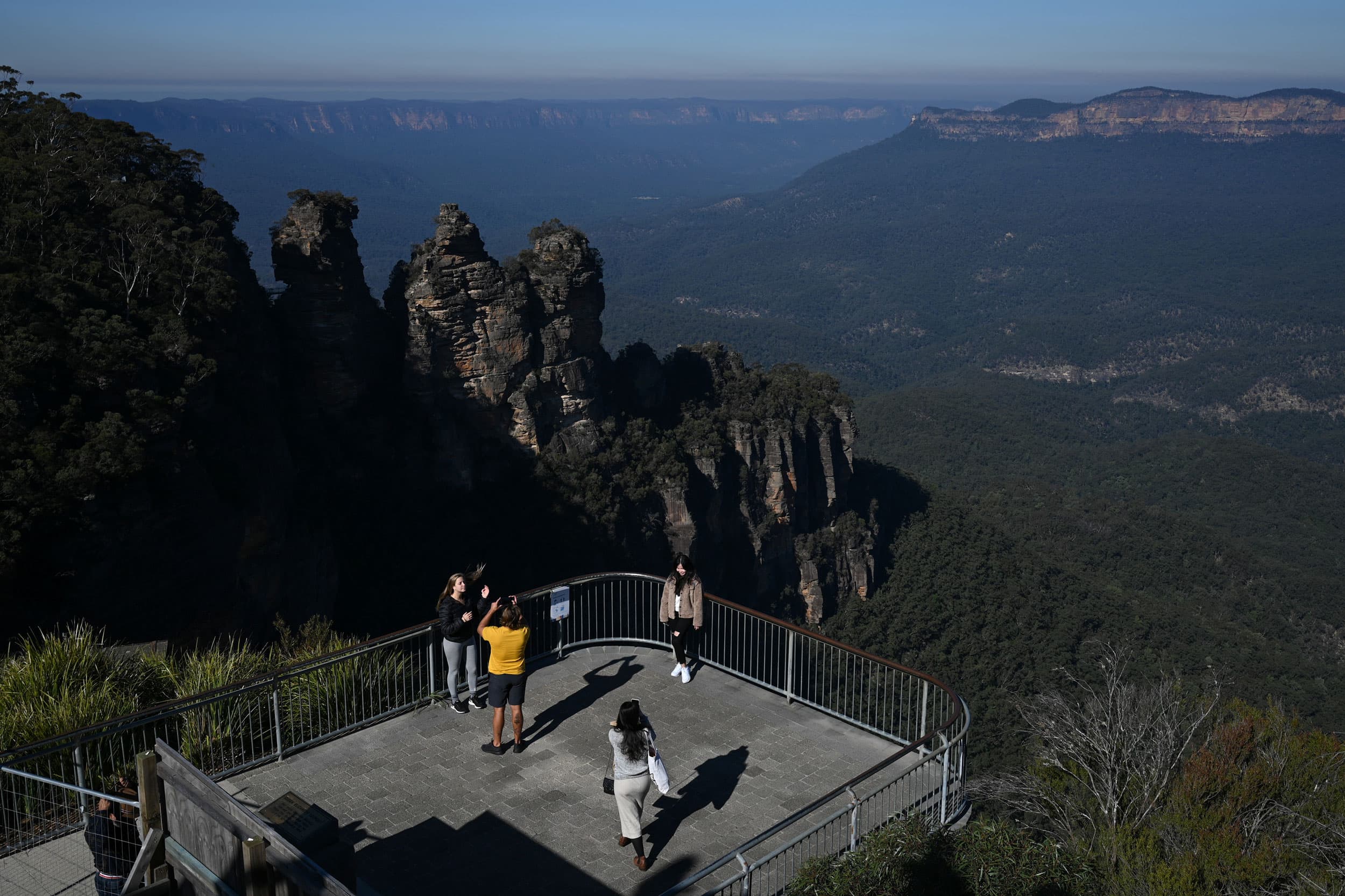 Tourists pose in front of a rock formation