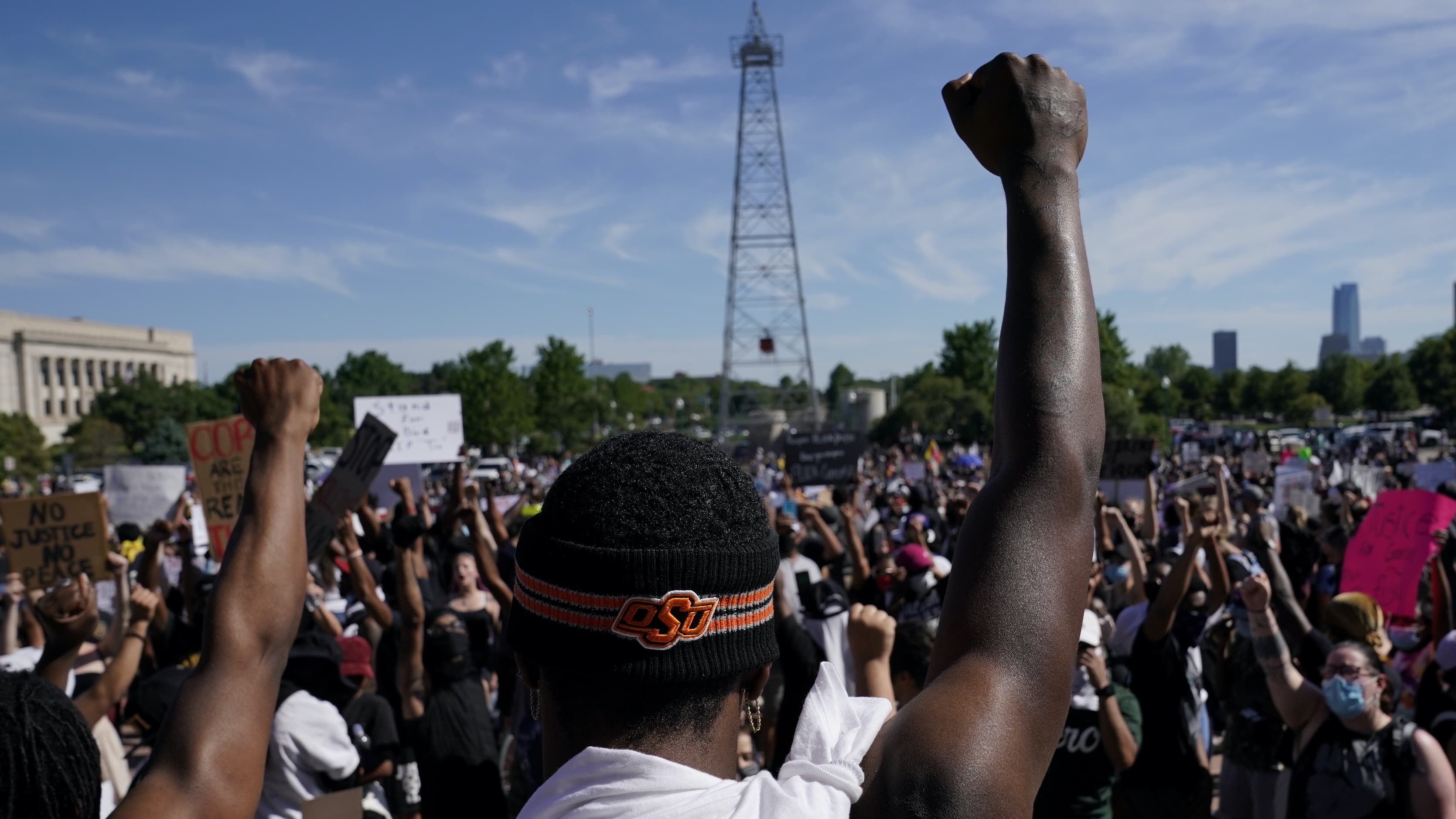A black man stands in a crowd with his fist raised in the air.