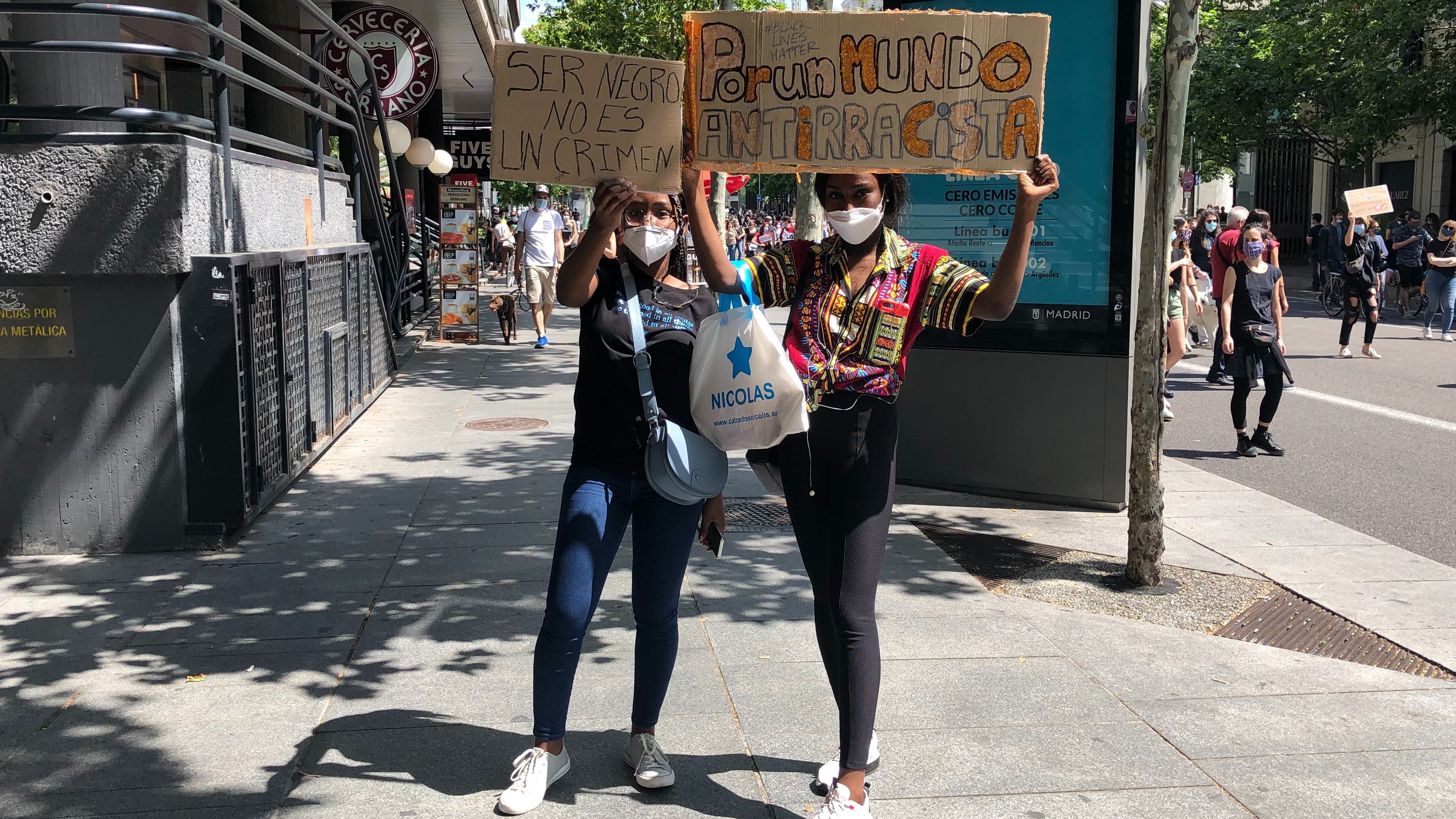 Two protesters hold signs with anti-racist messages