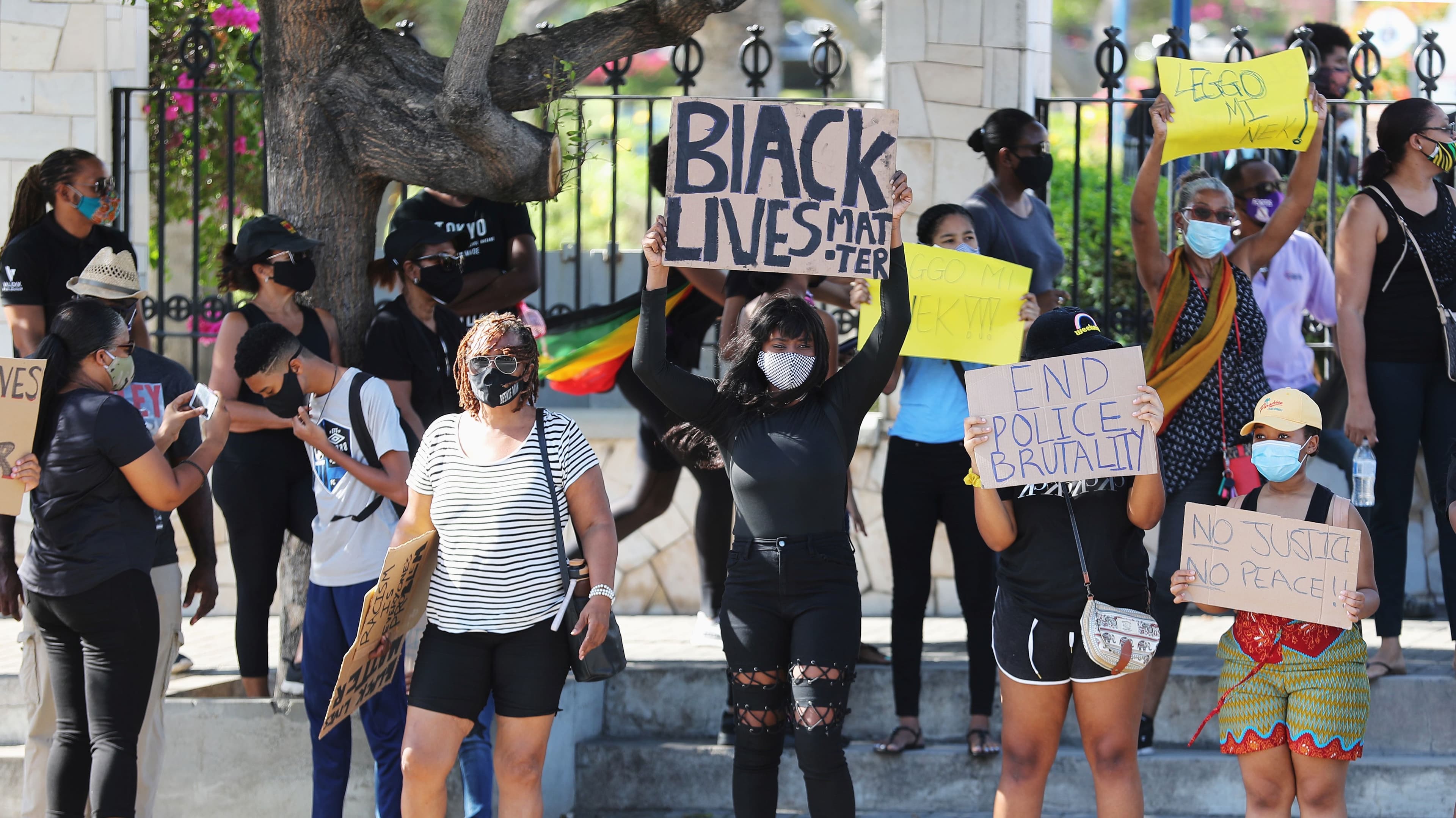 People hold posters as they take part in a demonstration against the death in Minneapolis police custody of George Floyd, at the Emancipation park in Kingston, Jamaica, June 6, 2020.