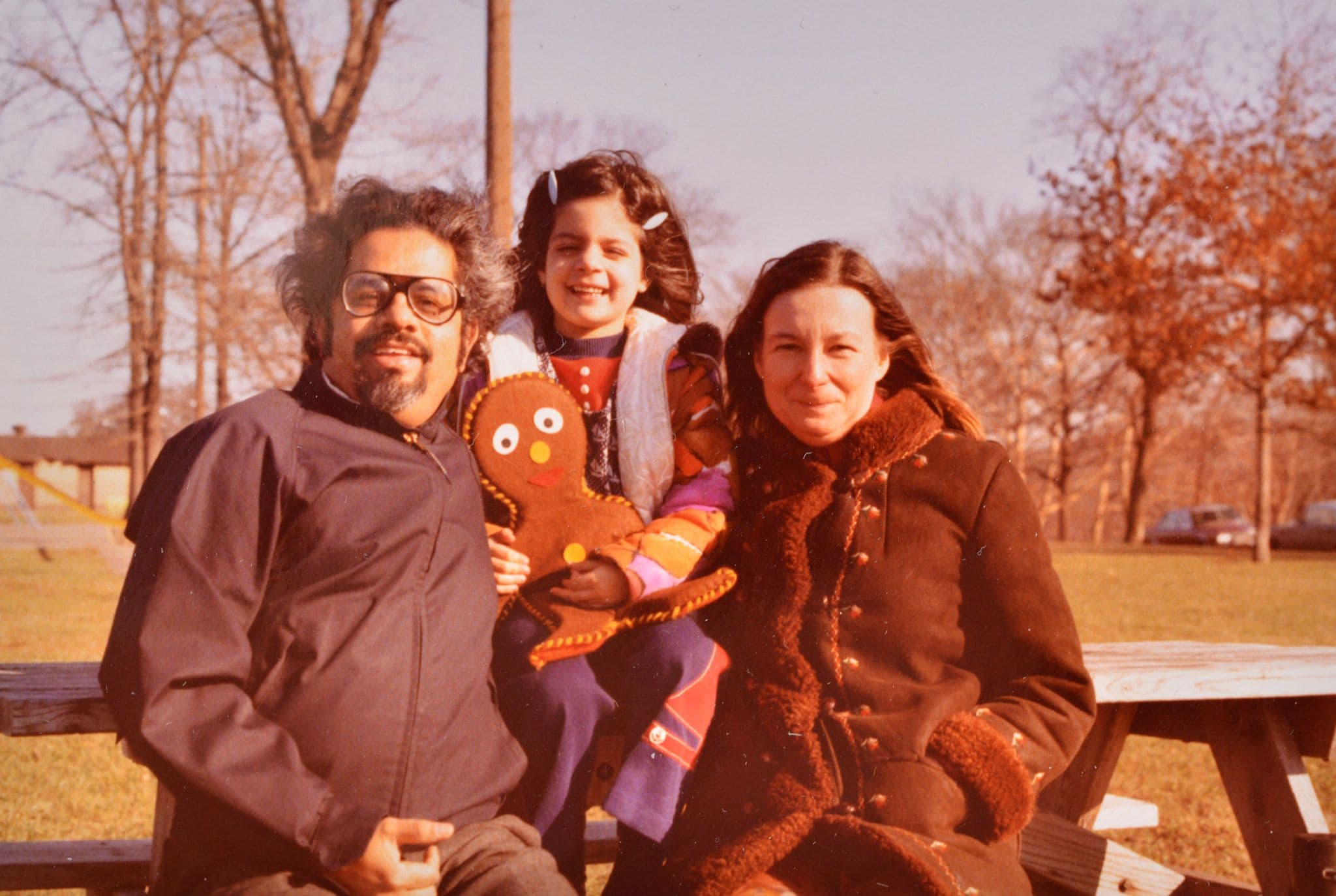 An older photo of a child between her parents