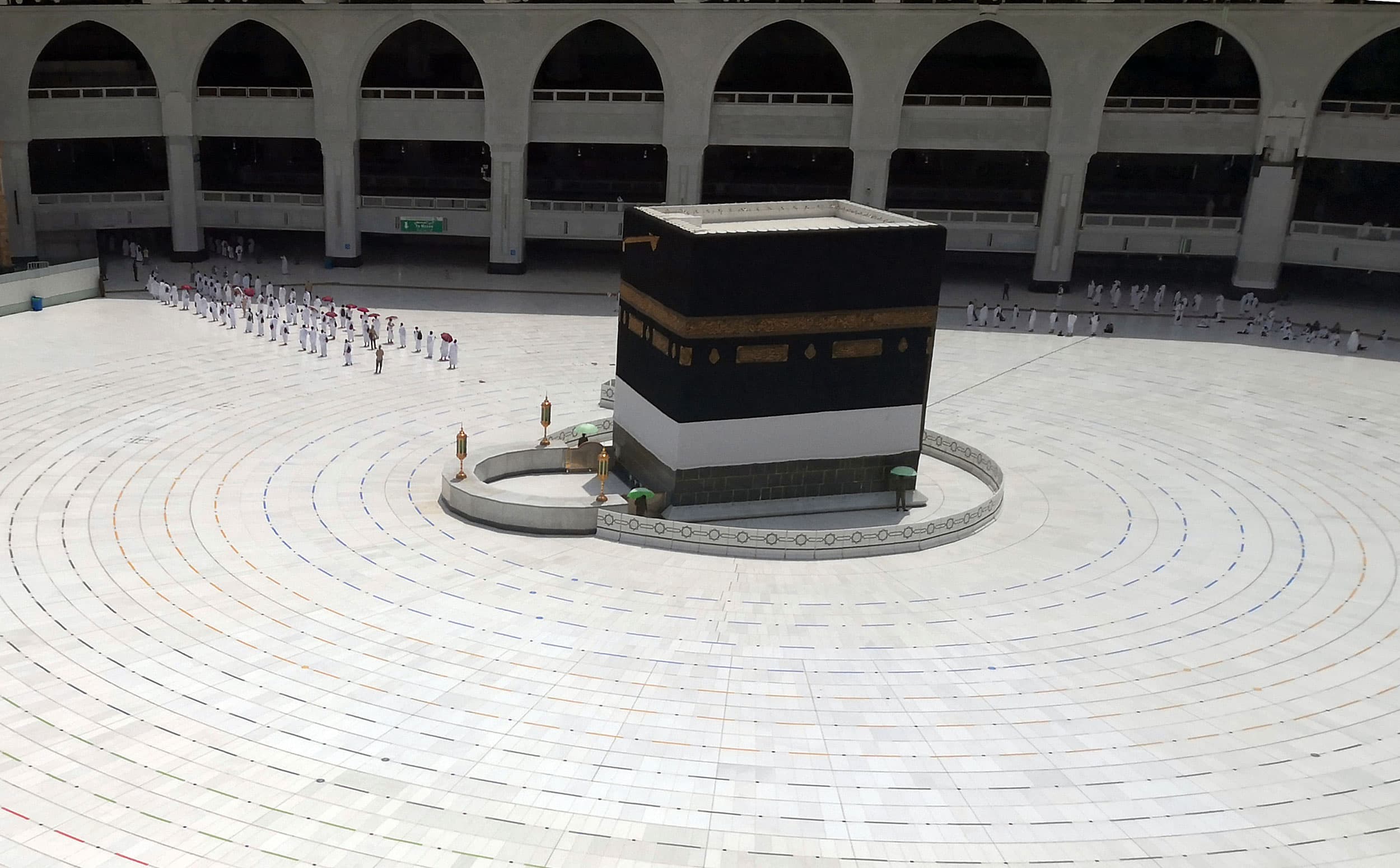 The Grand Mosque is shown nearly empty with several remaining pilgrims are lined upped on the side to leave.