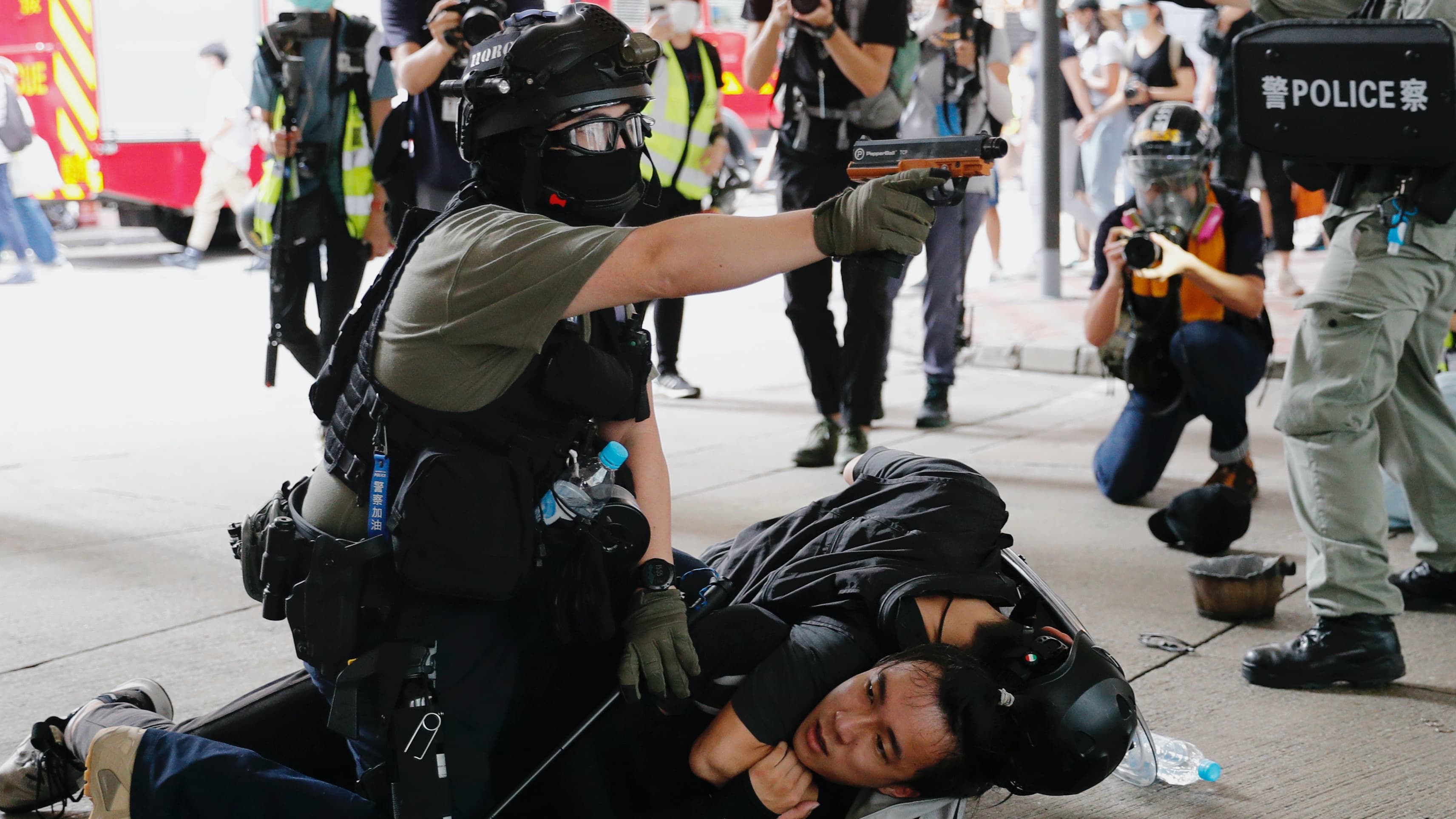 Riot police use water cannon to disperse protesters and one officer presses down on a protester
