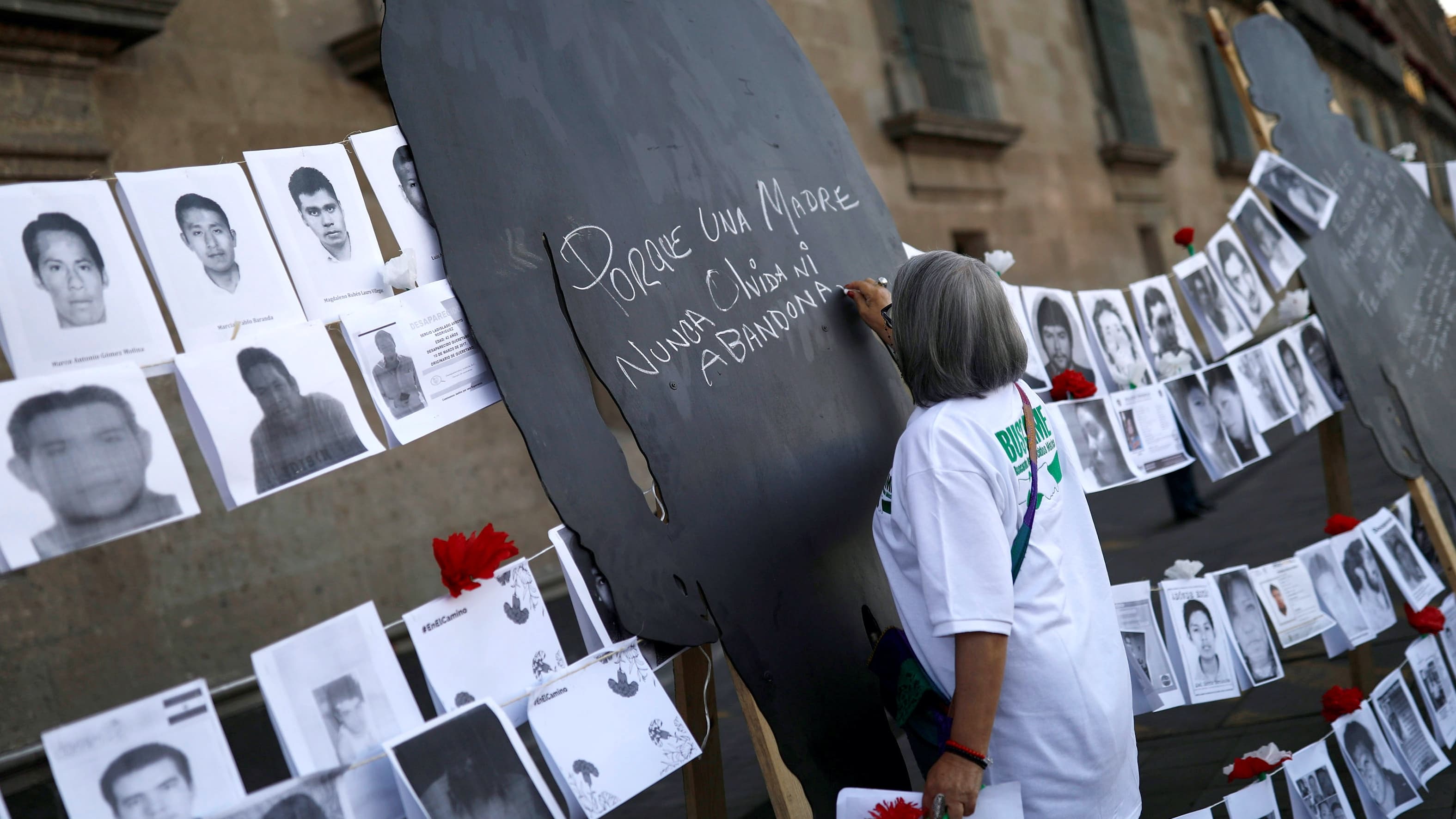 A woman wearing a white shirt signs a black silhouette during a demonstration for mothers of enforced disappearances