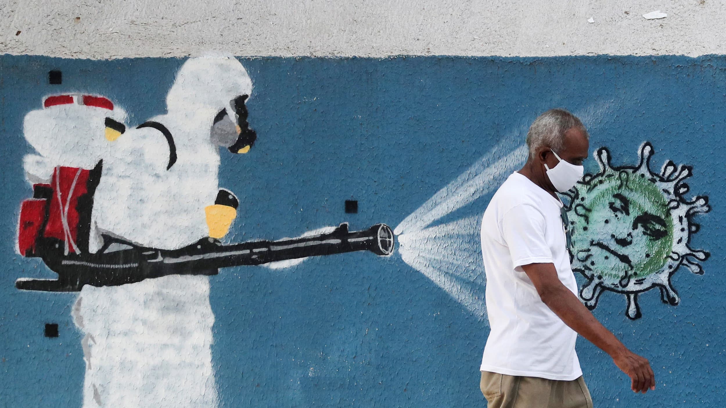 A painting on a wall shows a person dressed in full head to two medical protective gear with a red backpack and spray hose.