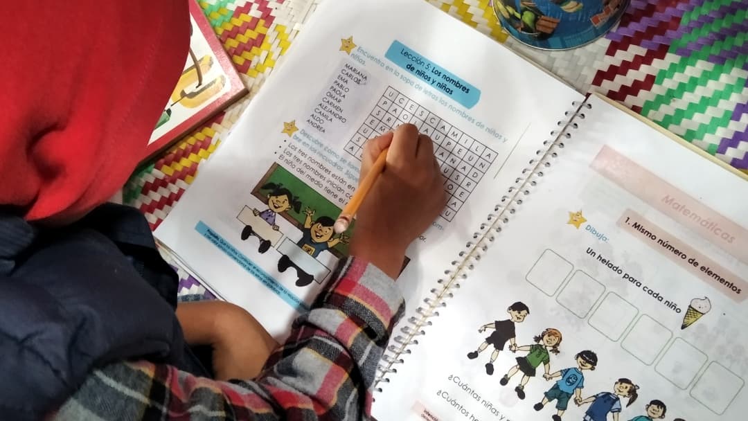 A student hovers over a notebook and fills in a lesson.