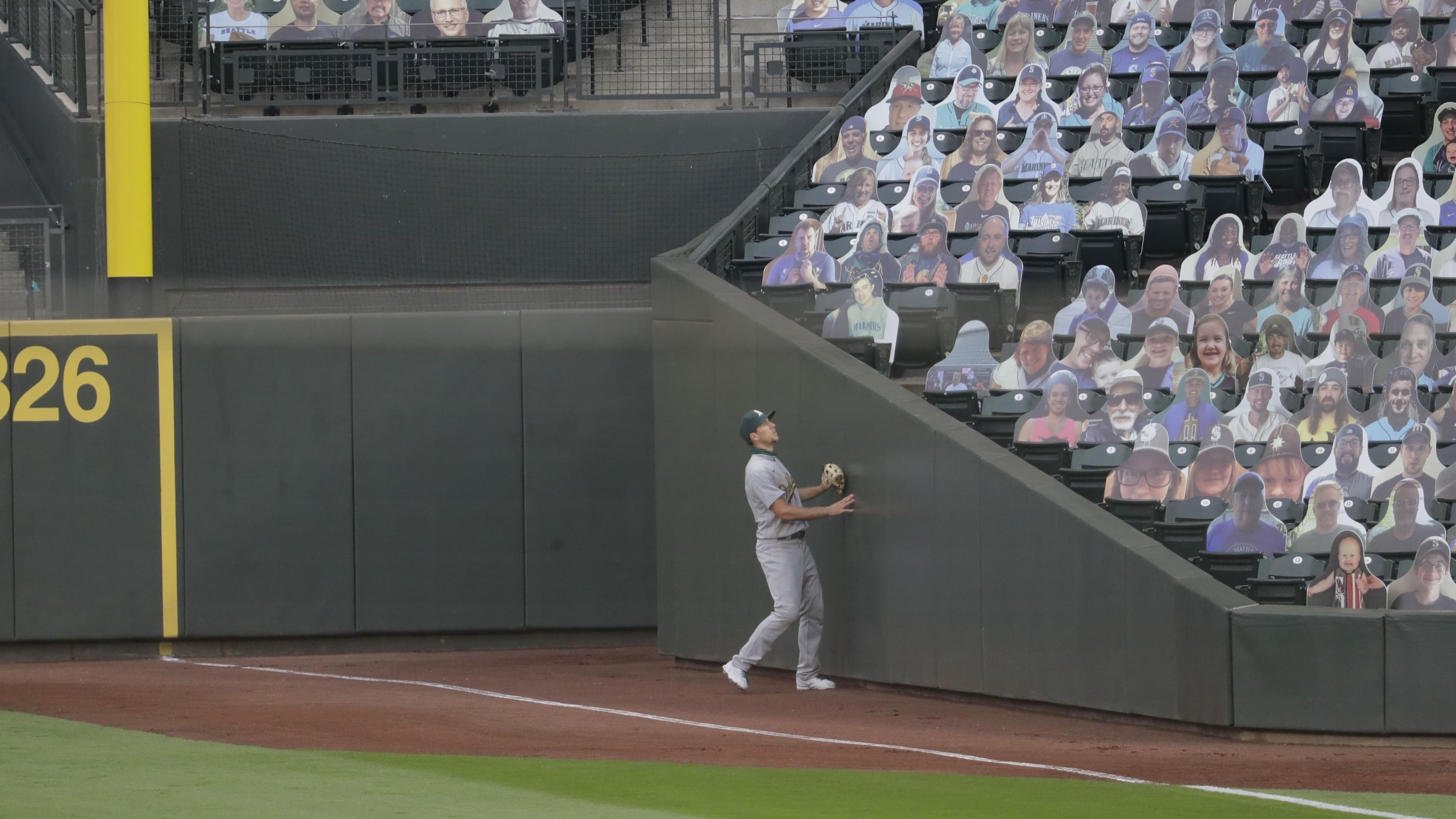 A baseball player watches a foul ball go into stands filled with photos of fans.