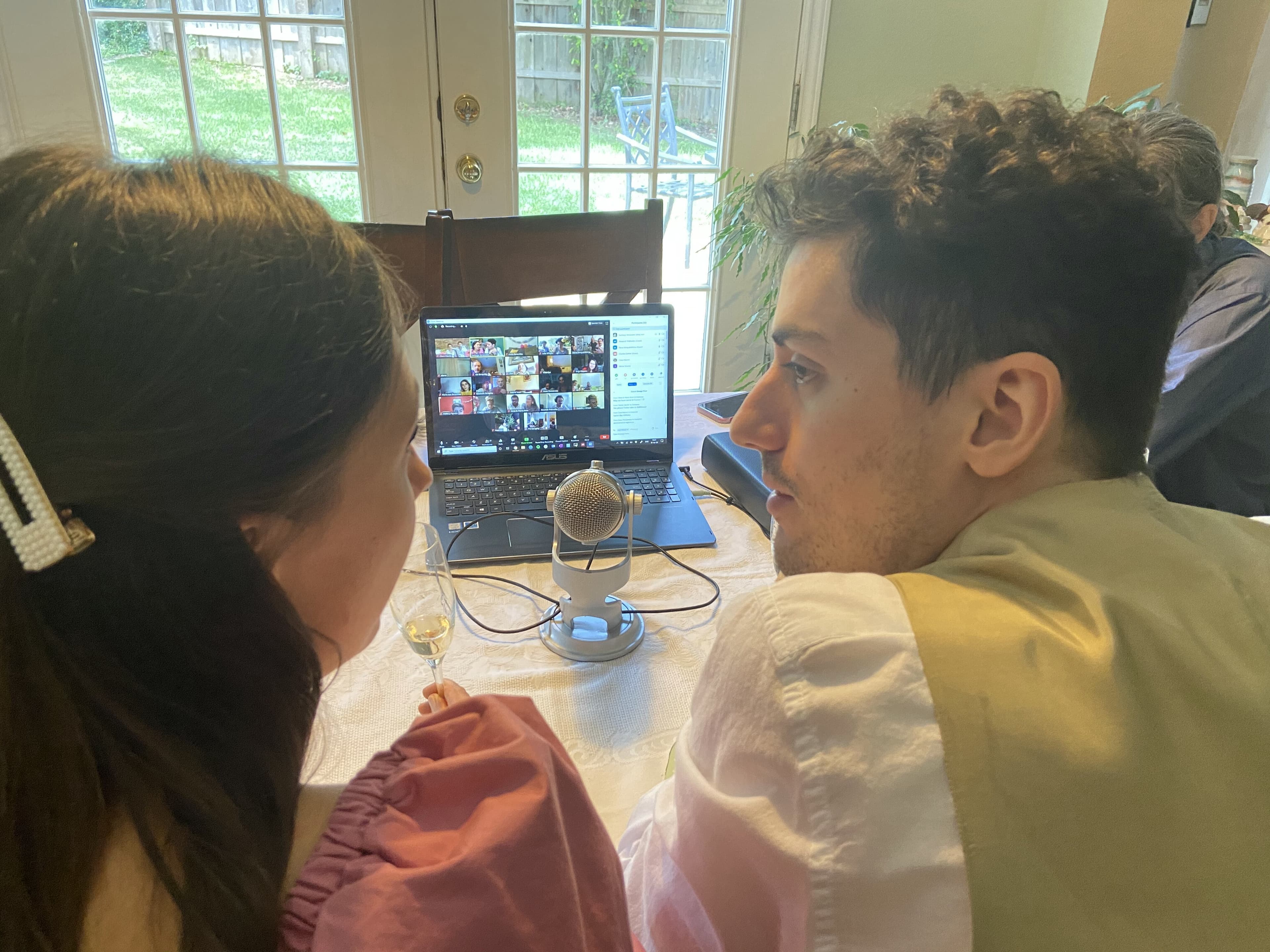 A man and woman set up the mic near a computer at a table