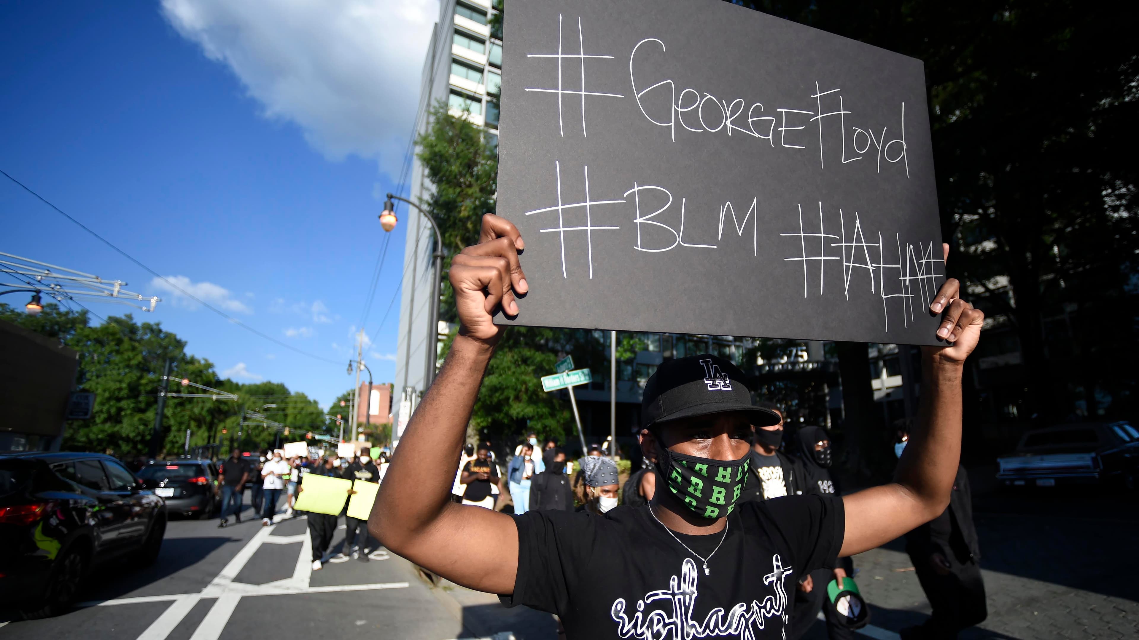 A demonstrator holding a sign reading #GeorgeFloyd and #BLM marches near Ebenezer Baptist Church in Atlanta, Georgia, May 30, 2020.