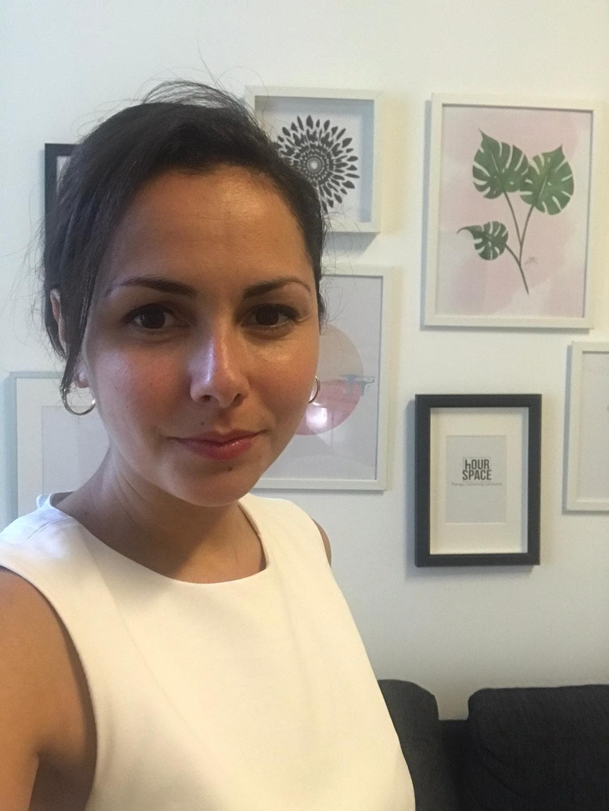 A white woman with brown hair pulled back wears a white blouse in a selfie photo