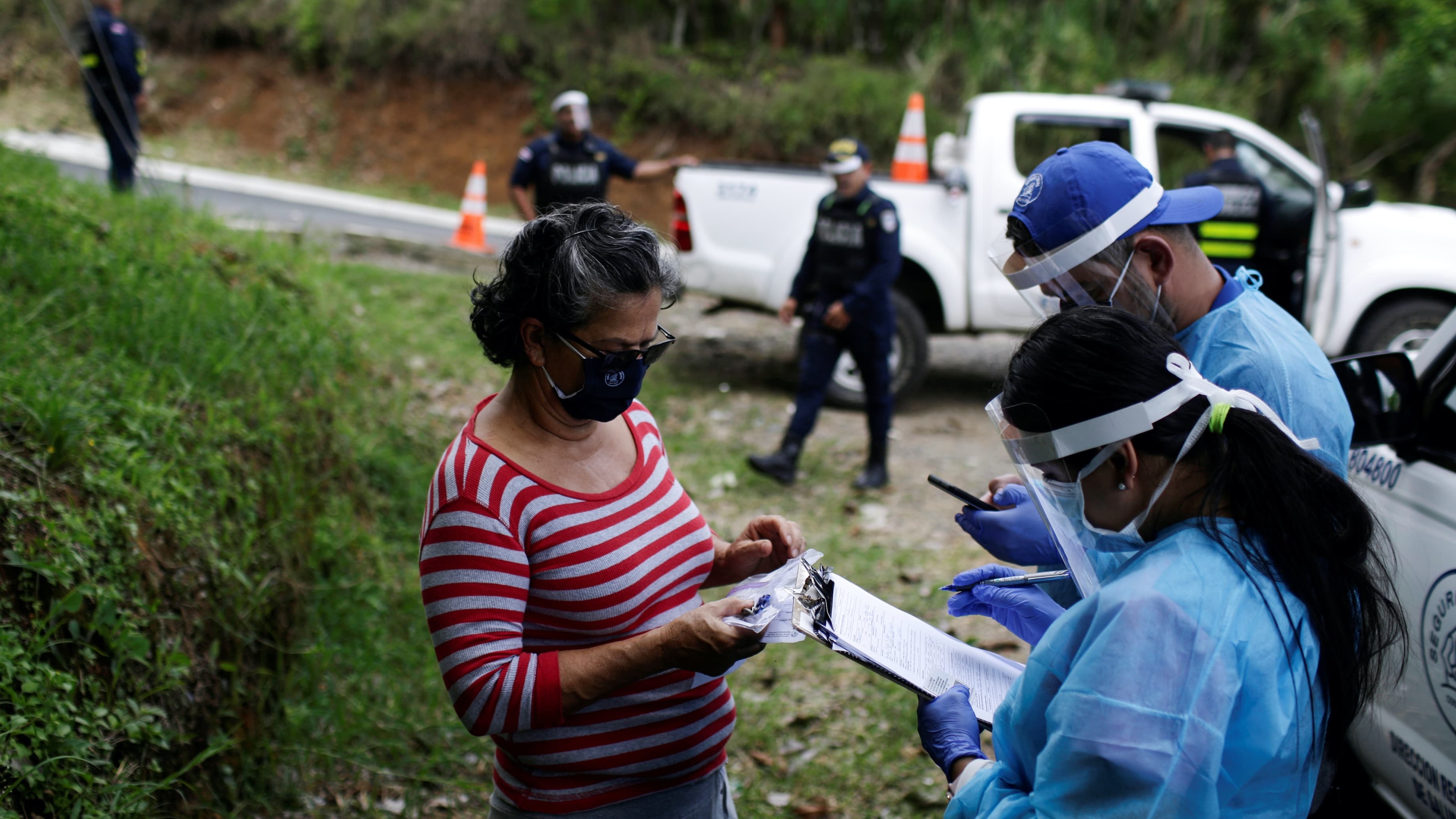 Health workers instruct a woman before taking a swab for the coronavirus disease (COVID-19) test.