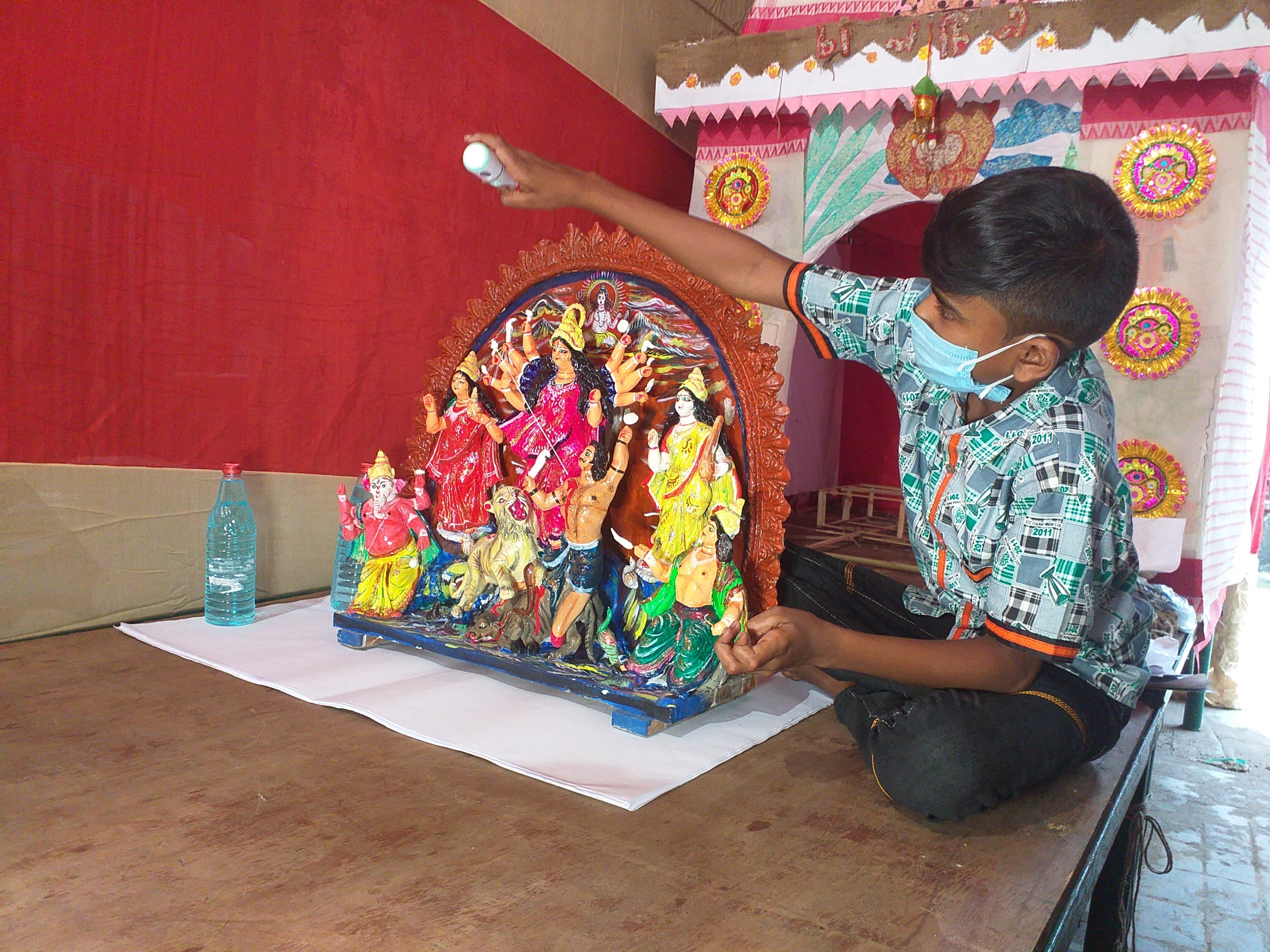 A little boy sanitizes a small idol.