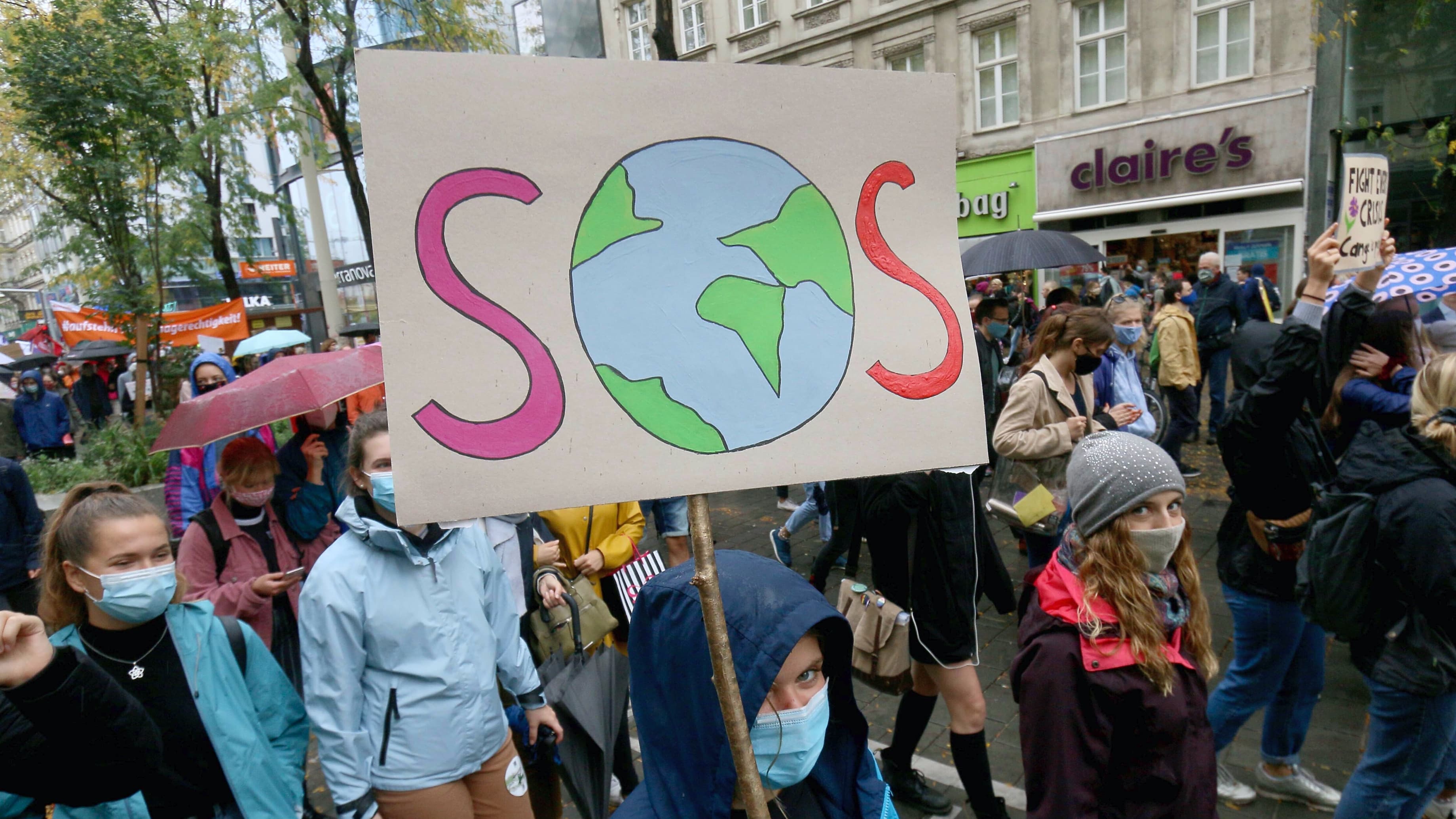 A protester holds a sign that reads SOS among other protesters on a street in Austria.