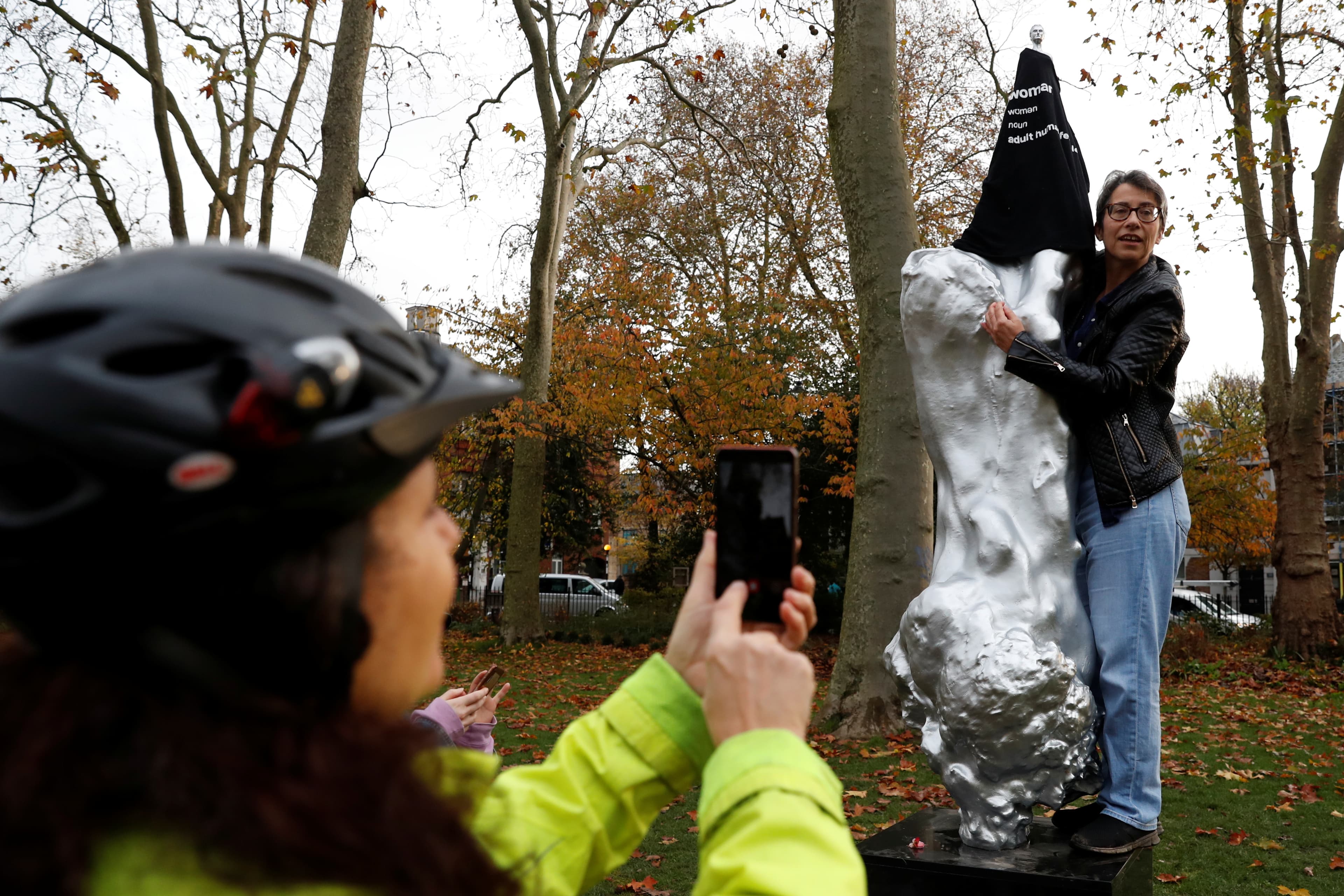 A protester covers with a T-shirt the Mary Wollstonecraft statue by artist Maggi Hambling, in Newington Green, London, Britain, Nov. 11, 2020.