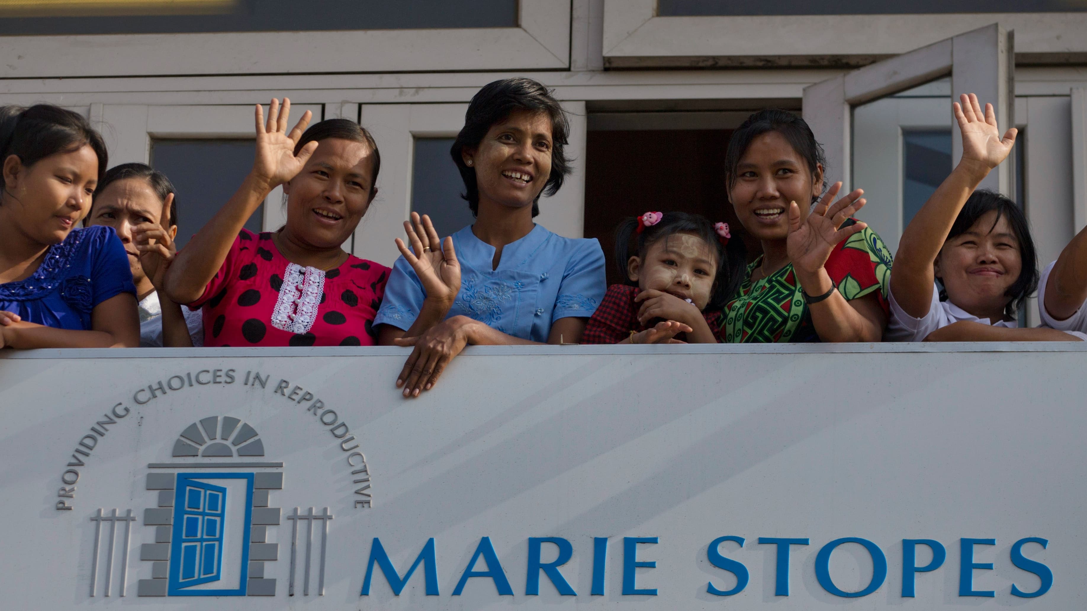 Patients and staff members of Marie Stopes International (MSI) Clinic wave to Danish delegation members.