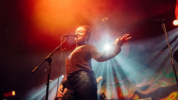 Meklit Hadero performs under red-orange lighting